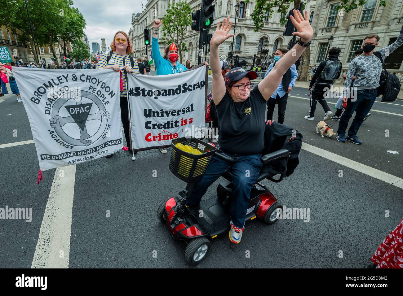 London, UK. 26 Jun 2021. The march arrives in Whitehall and passes Downing Street and is met by the disabled group - The Peoples Assembly leads a national demonstration to #DemandANewNormal. They aim to confront the approach of the current government. Specifically they are against the the public sector pay freeze, lack of sick pay, fire and rehire policies as well as the Police, Crime, Sentencing and Courts Bill. The protest is supported by many Unions including Unite and PCS, organisations like Free Palestine, Stand Up to Racism and environmental groups like Extinction Rebellion. The March st Stock Photo