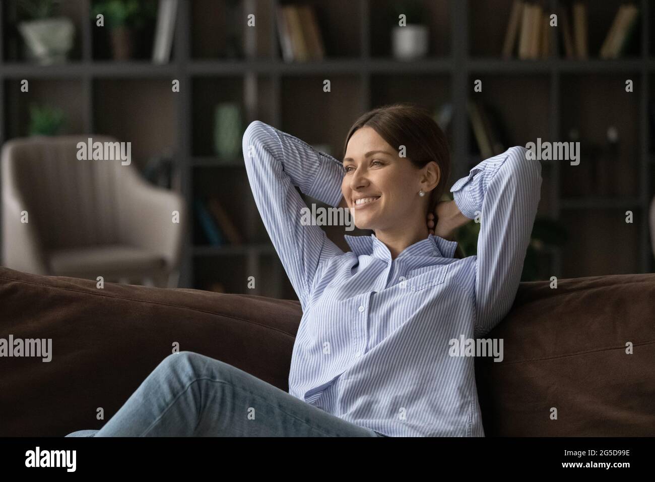 Smiling young woman relaxing on cozy sofa Stock Photo - Alamy