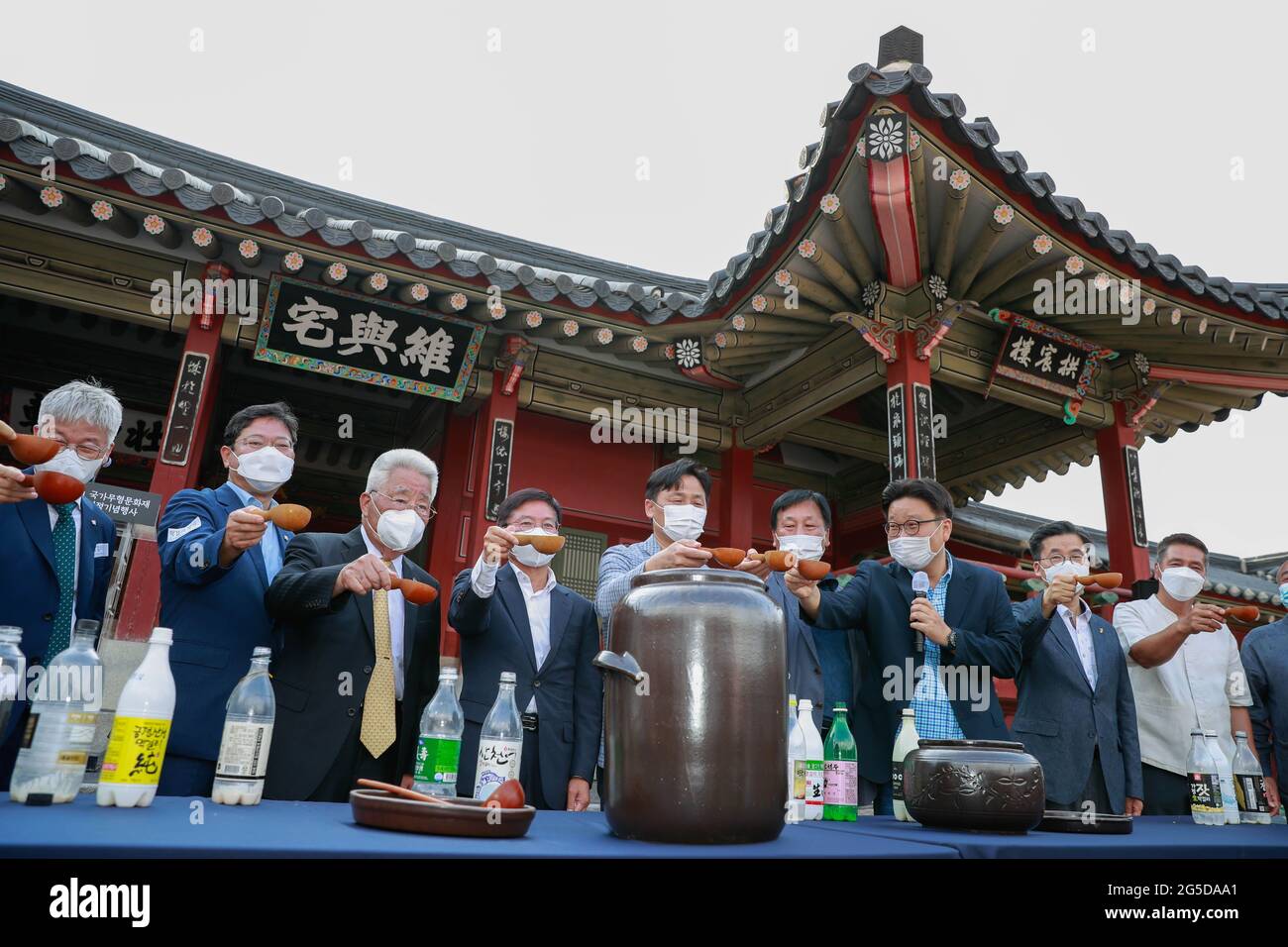 Suwon, South Korea. 26th June, 2021. Guests have a toast during a celebration ceremony at Hwaseong Haenggung Palace in Suwon, South Korea, June 26, 2021. Makgeolli, a traditional Korean alcoholic beverage made from rice, has been listed as South Korea's national intangible cultural heritage recently. Credit: Wang Jingqiang/Xinhua/Alamy Live News Stock Photo