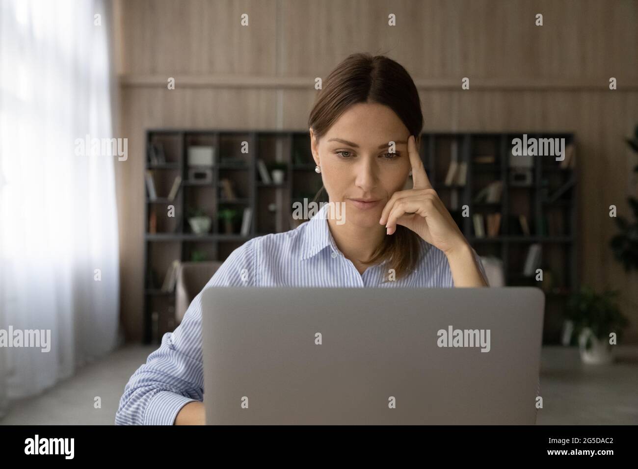 Concentrated thoughtful young business lady working on computer. Stock Photo