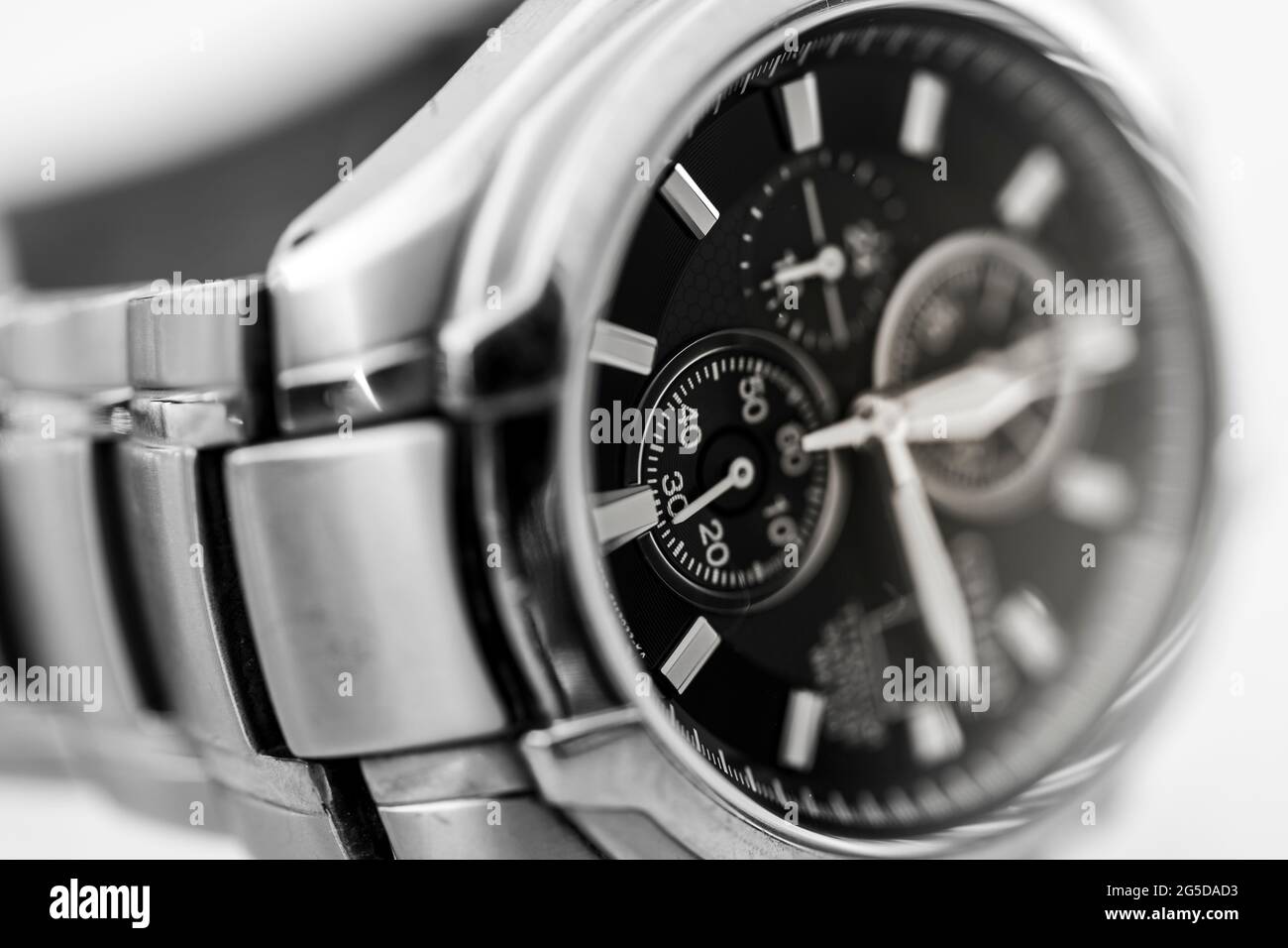 Monochrome black and white closeup image of a Citizen Eco Drive solar powered titanium metal man's wristwatch face showing clock hands and the strap Stock Photo