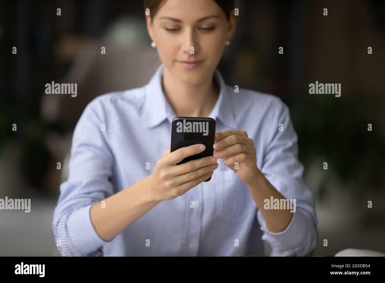 Young business woman using smartphone application in office. Stock Photo