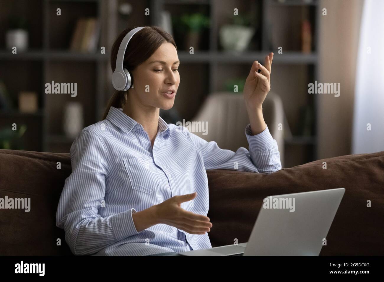 Happy millennial woman in headphones holding computer video call ...