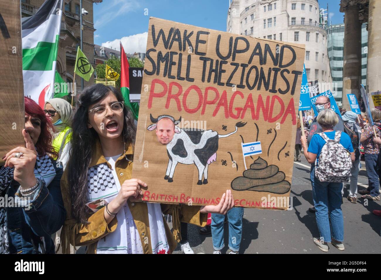 London, UK. 26th June 2021. Wake Up and Smell the Zionist Propaganda poster.  Over five thousand joined the People's Assembly march through London against the failures of the Tory government during the pandemic, acting too late, handing out contracts to cronies and failing to reward key workers for their sacrifices. They demanded a 'new normal' with an end to NHS privatisation, decent housing, real action over climate change, decent housing, an end to unfair employment practices and the sacking of corrupt politicians. Peter Marshall/Alamy Live News Stock Photo