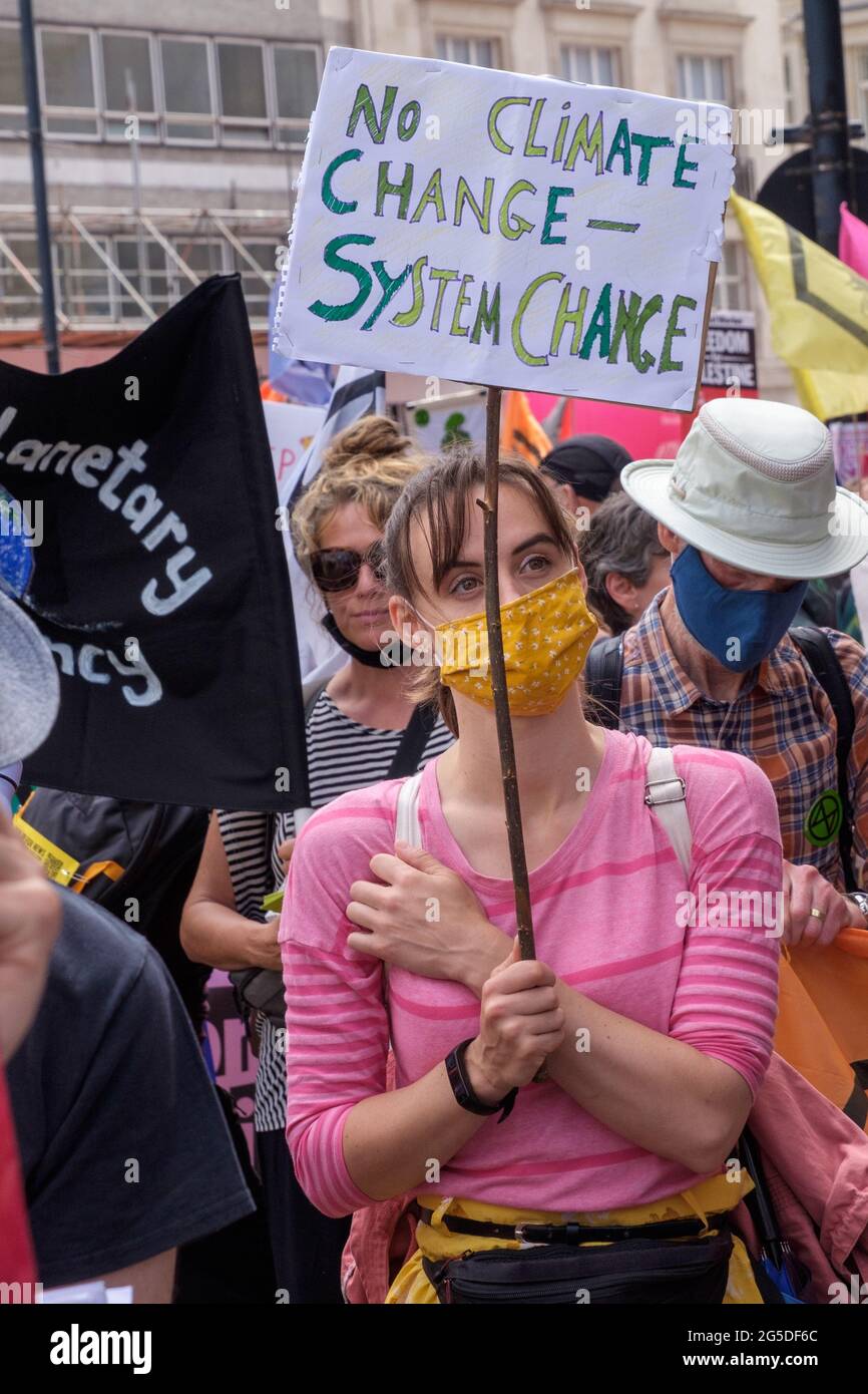 London, UK. 26th June 2021. Woman calls for system change - not climate change. Over five thousand joined the People's Assembly march through London against the failures of the Tory government during the pandemic, acting too late, handing out contracts to cronies and failing to reward key workers for their sacrifices. They demanded a 'new normal' with an end to NHS privatisation, decent housing, real action over climate change, decent housing, an end to unfair employment practices and the sacking of corrupt politicians. Peter Marshall/Alamy Live News Stock Photo