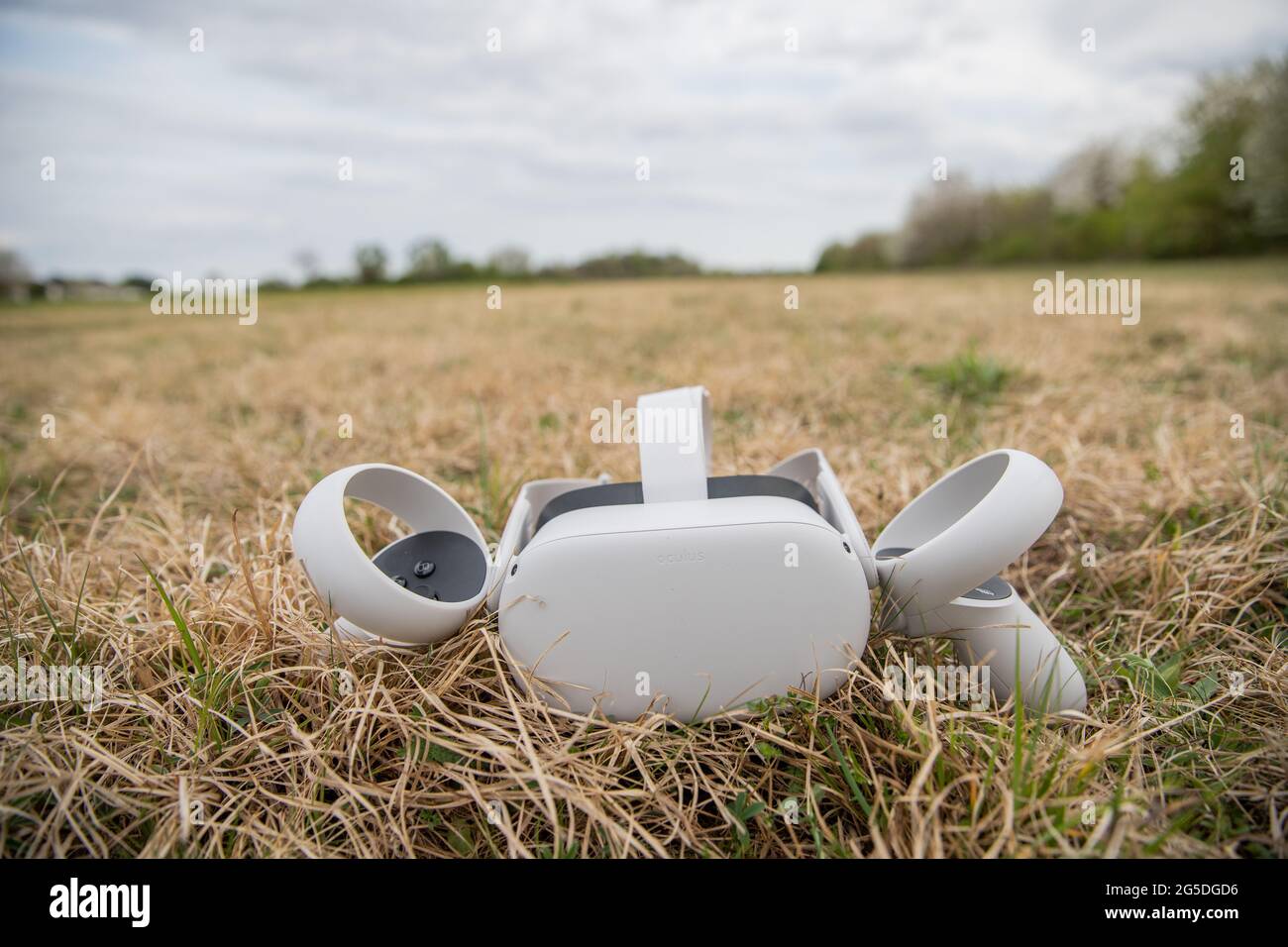Oculus Quest 2 virtual reality headset with controllers, resting on a lawn Stock Photo