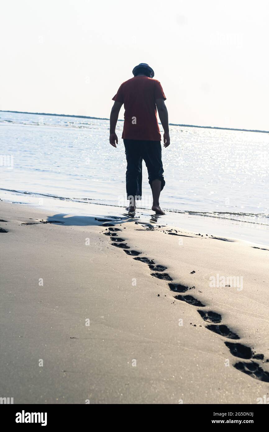 Footprints on the beach sand. Traces on the beach. Footsteps on the beach by the sea in summer. A man leaves footprints in the sand. Stock Photo