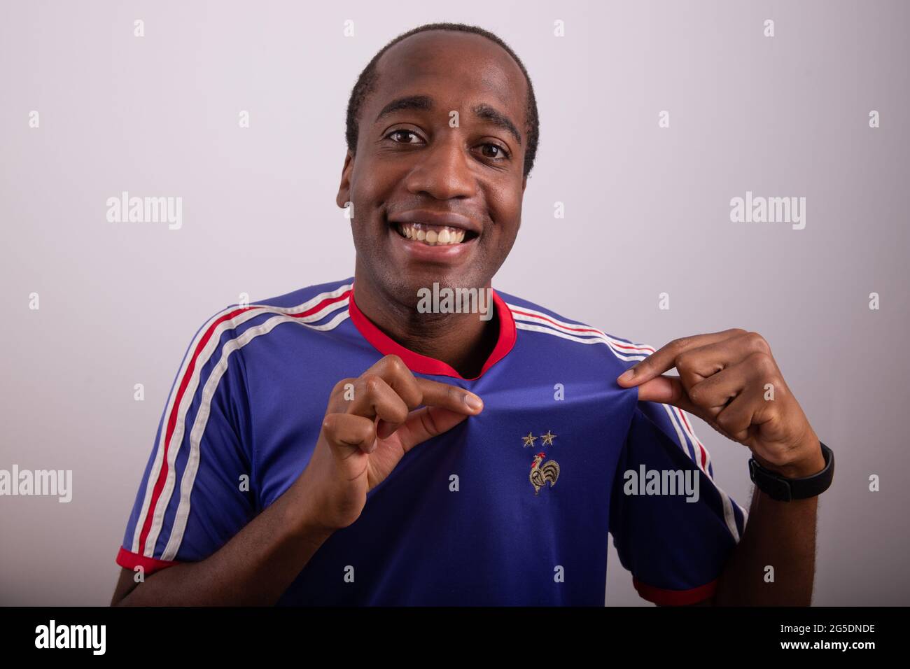 French fan is happy and celebrates the victory of France, he wears the jersey of the french national football team and shows the french rooster. Happy Stock Photo