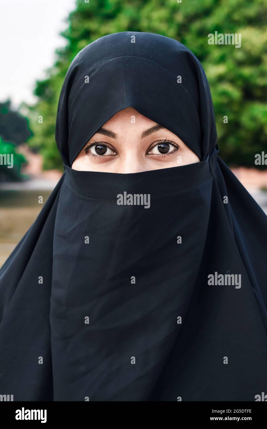 Closeup of beautiful woman face covered with hijab. Perfect shiny eyes of a Muslim girl. Young niqab girl portrait with the background. Stock Photo