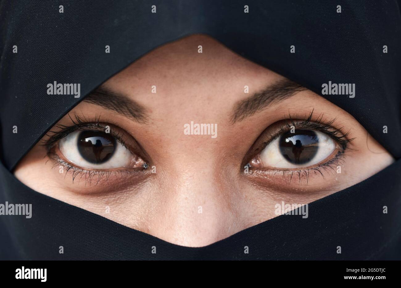 Closeup of beautiful woman face covered with hijab. Perfect shiny eyes of a Muslim girl. Young niqab girl portrait. Stock Photo