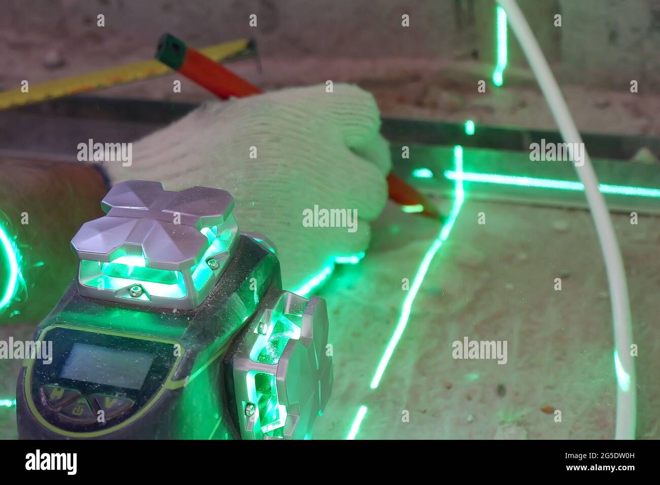 the builder measures the repair lines using a green laser level, Stock Photo