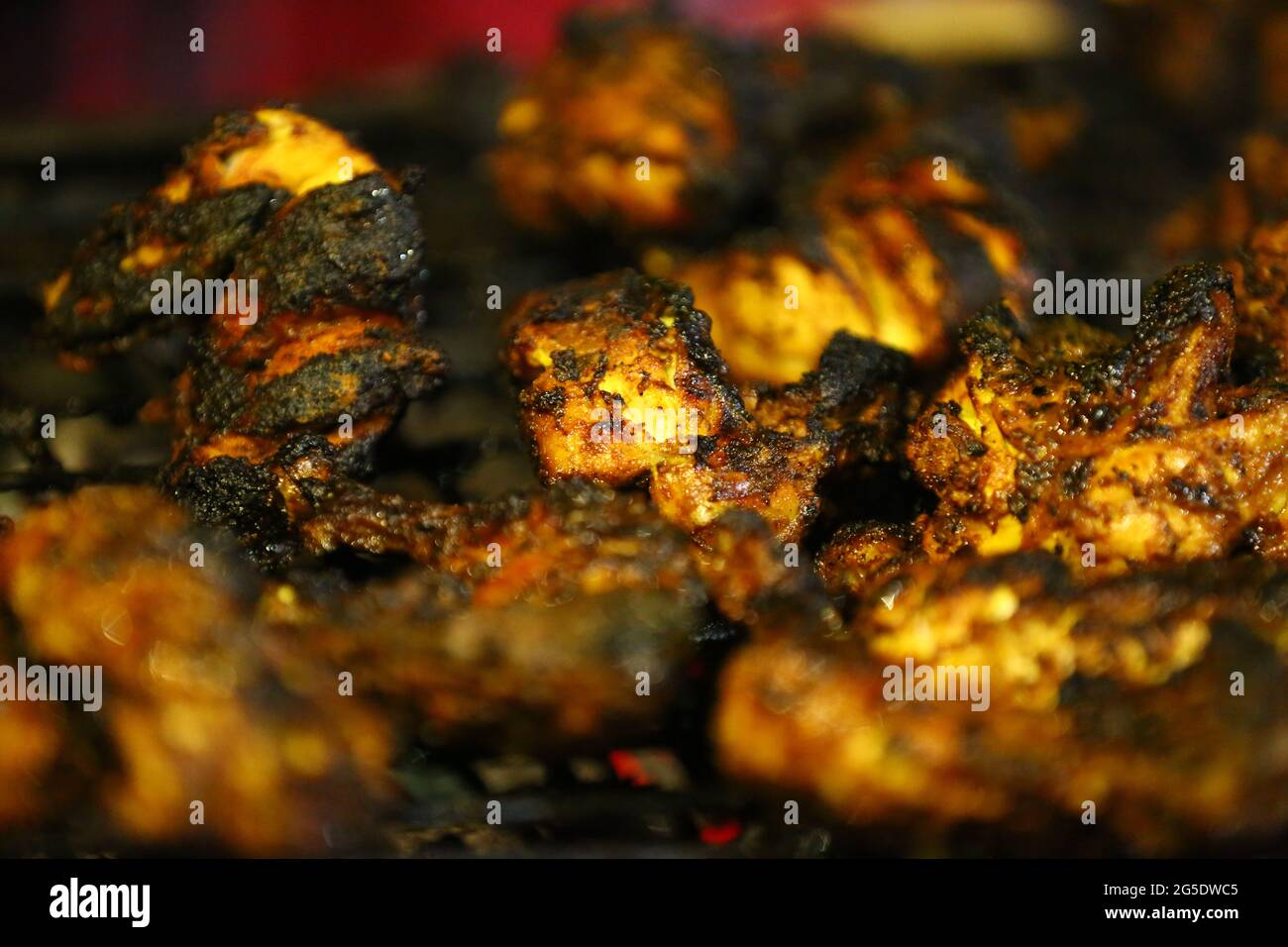 Tasty chicken legs and wings on the grill with fire flames Stock Photo