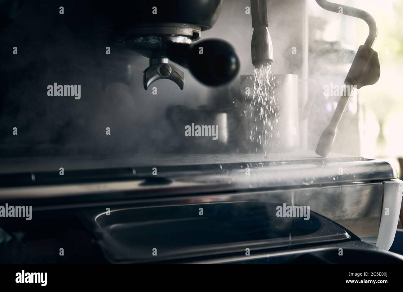 Closeup of a professional steel coffee machine releasing steam and