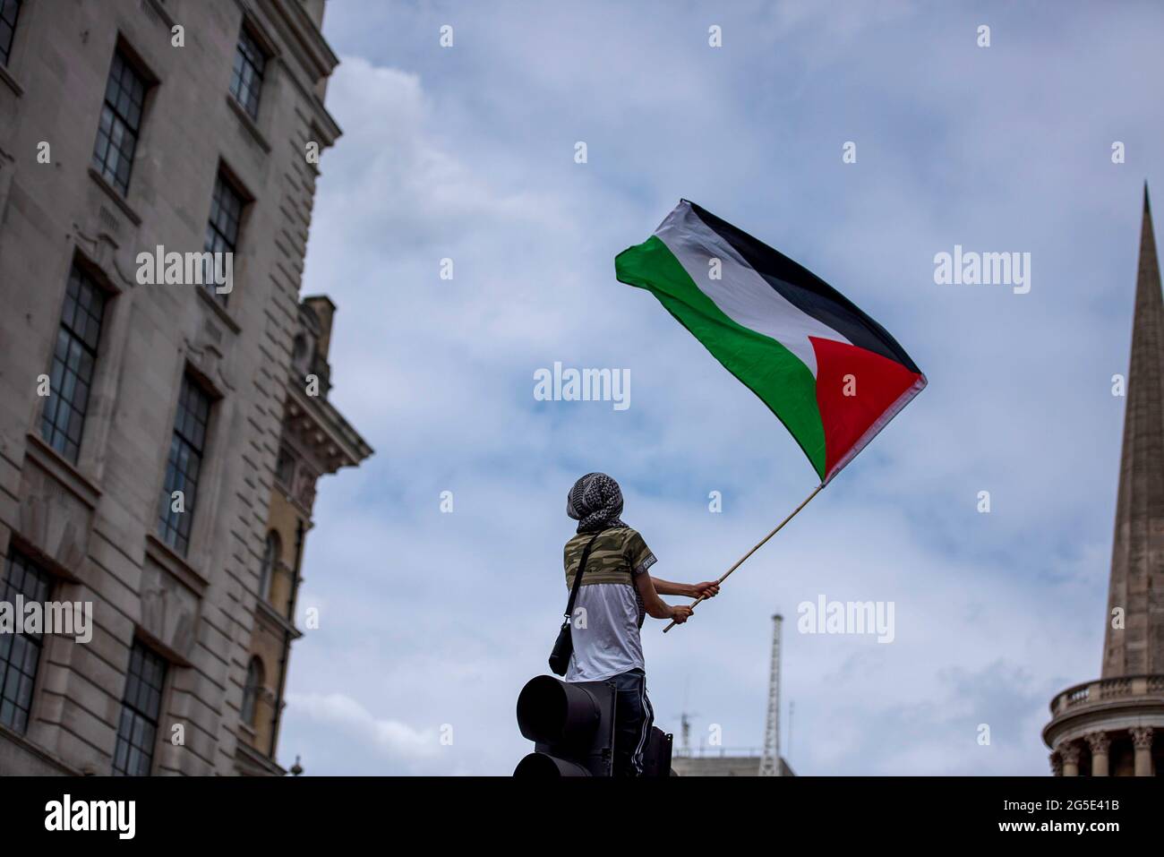 London, UK. 26th June, 2021. An activist waves a large Palestinian flag during the demonstration. People's Assembly held a National Protest in London demonstrating a plethora of issues from the Palestine and Israel conflict, coronavirus issues and the government handling of the pandemic, the police crime bill, and anti-arms matters. Credit: SOPA Images Limited/Alamy Live News Stock Photo