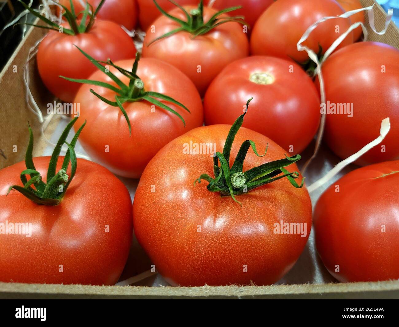 Close-up shot of a lot of ripe fresh tomatoes in a wooden box for sale at a farmer's market and in an organic store. Healthy food, vitamins.Raw vegeta Stock Photo