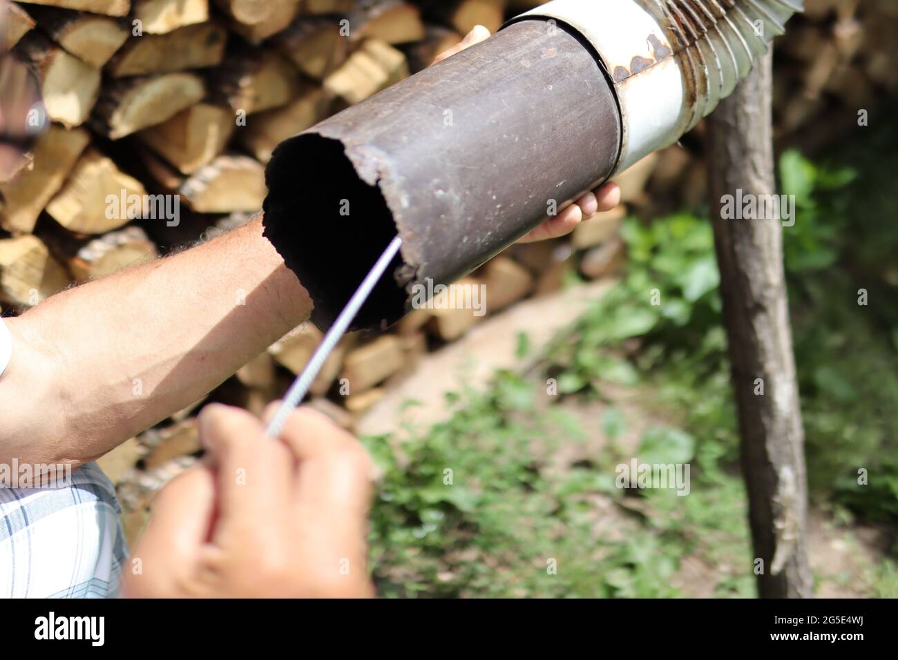 Close up of man hand cleaning chimney pipe outside with tool. Cleaning a wood burning stove concept. Chimney sweep cleaning Stock Photo