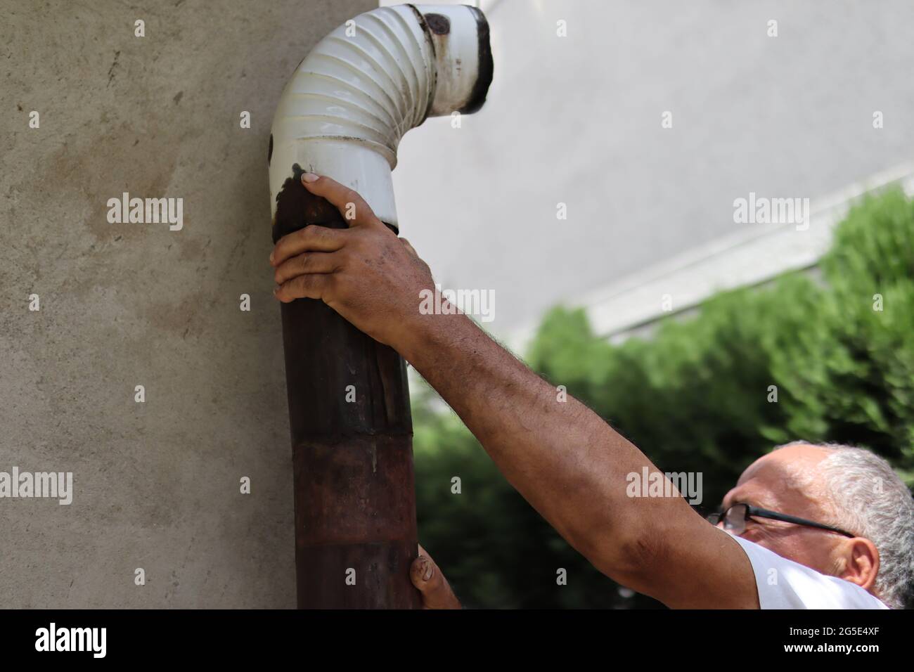 Man installing outdoor old tin stovepipe for a home wood burning stove. Close up and copy space Stock Photo