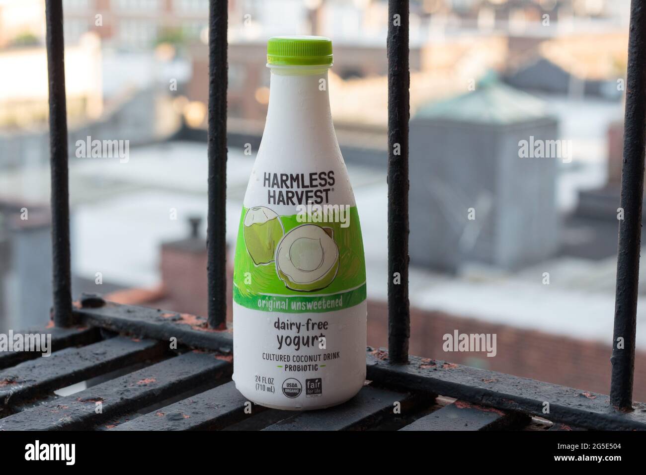 bottle of Harmless Harvest brand original, unsweetened, organic dairy-free drinkable yogurt, probiotic cultured coconut milk, on a fire escape Stock Photo