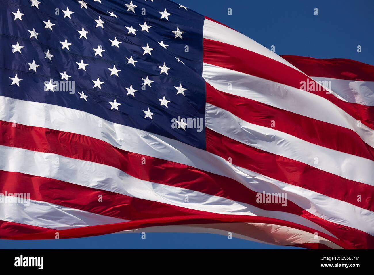 American Flag Waving In Wind Against a Deep Blue Sky Stock Photo - Alamy