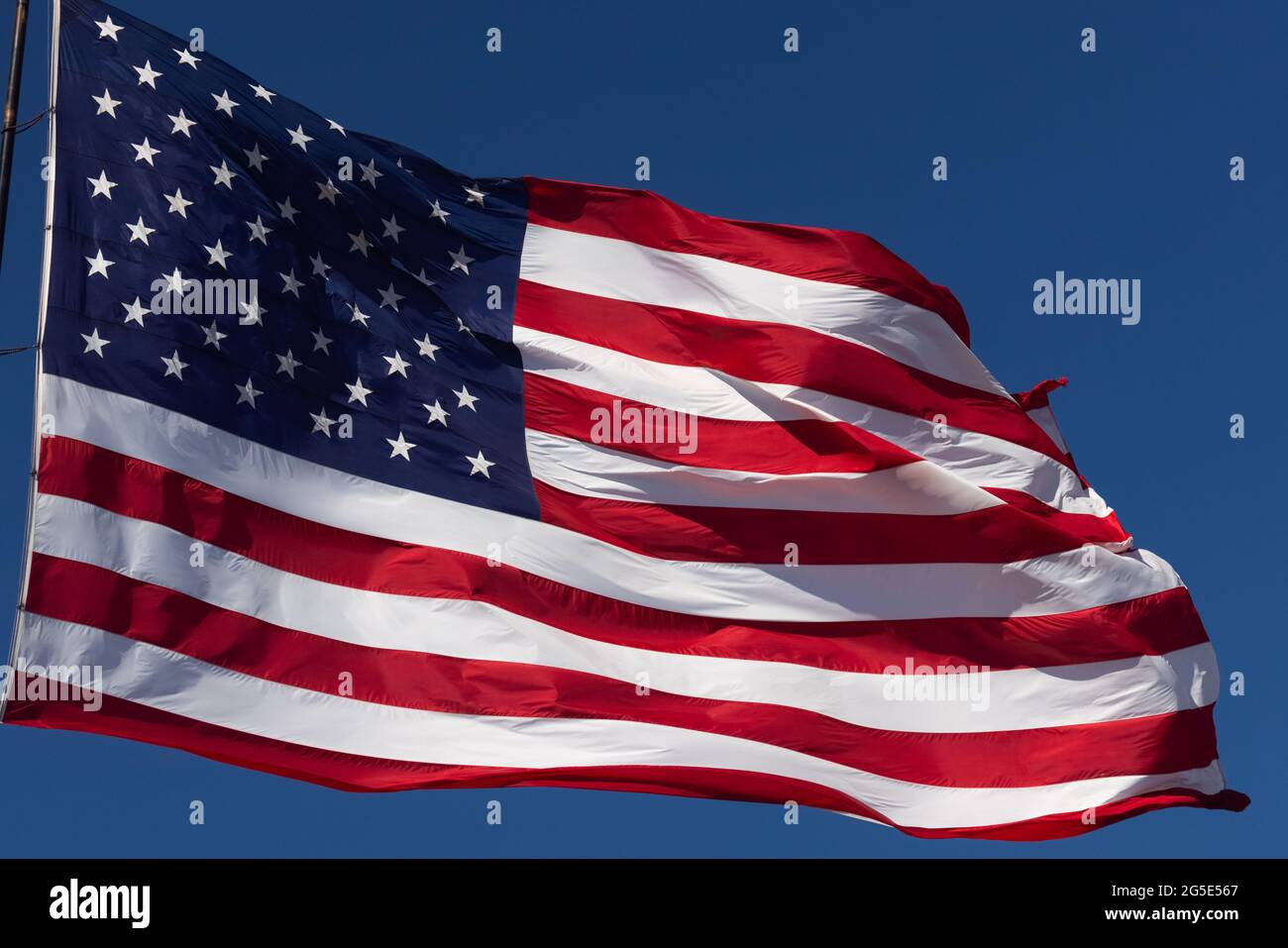 American Flag Waving In Wind Against a Deep Blue Sky Stock Photo - Alamy