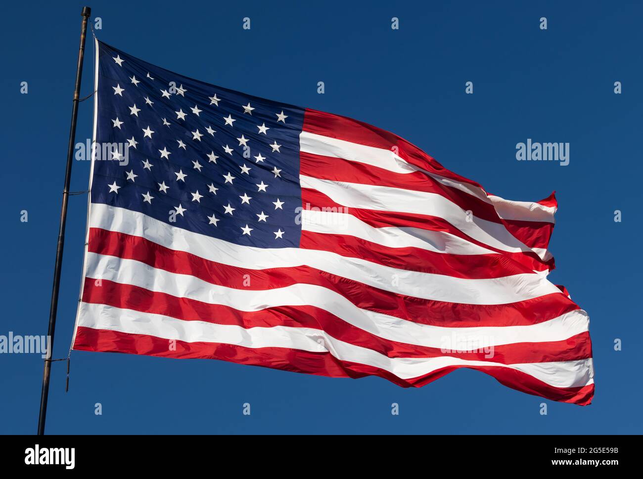 American Flag Waving In Wind Against a Deep Blue Sky Stock Photo - Alamy