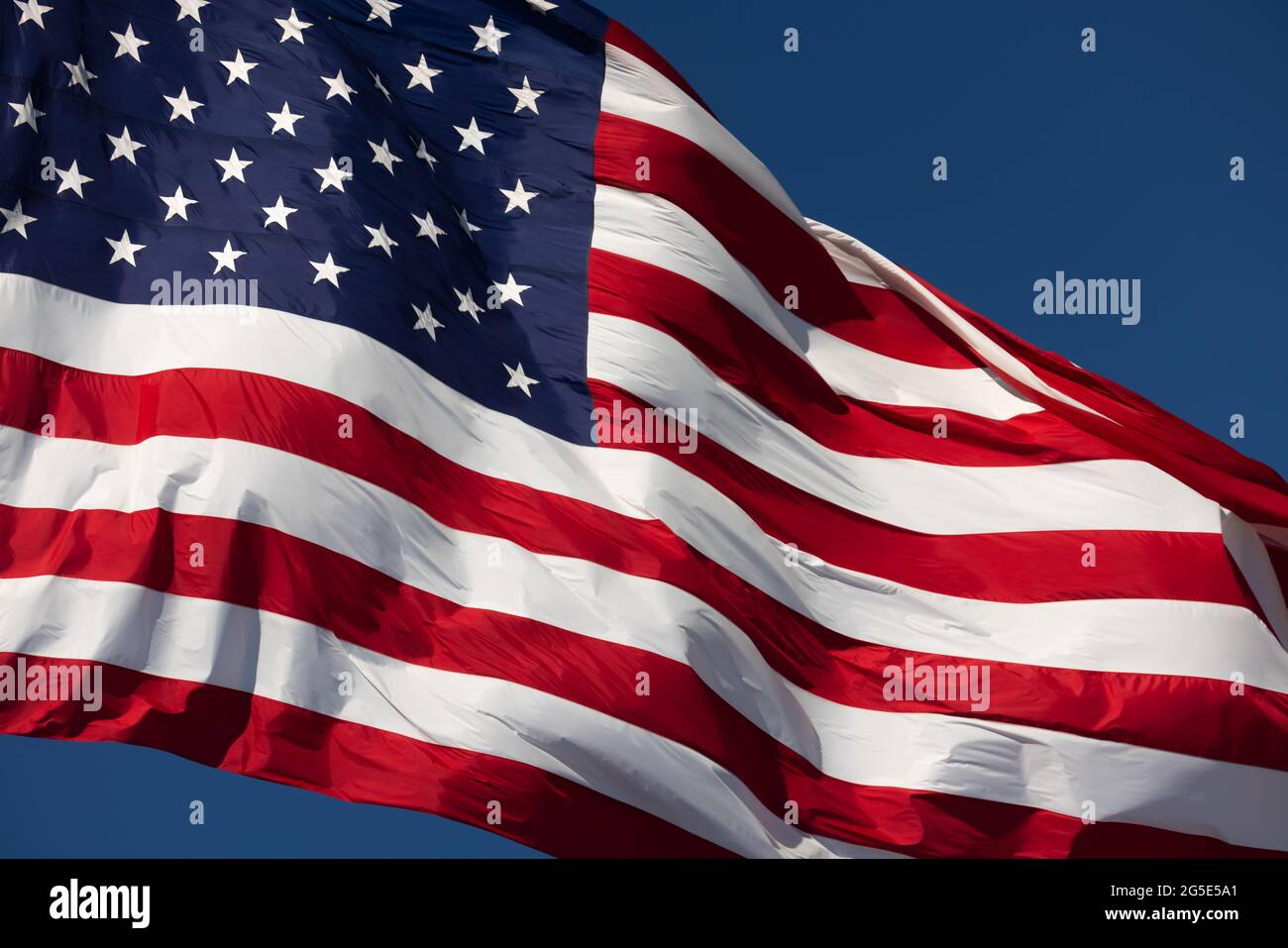 American Flag Waving In Wind Against a Deep Blue Sky Stock Photo - Alamy