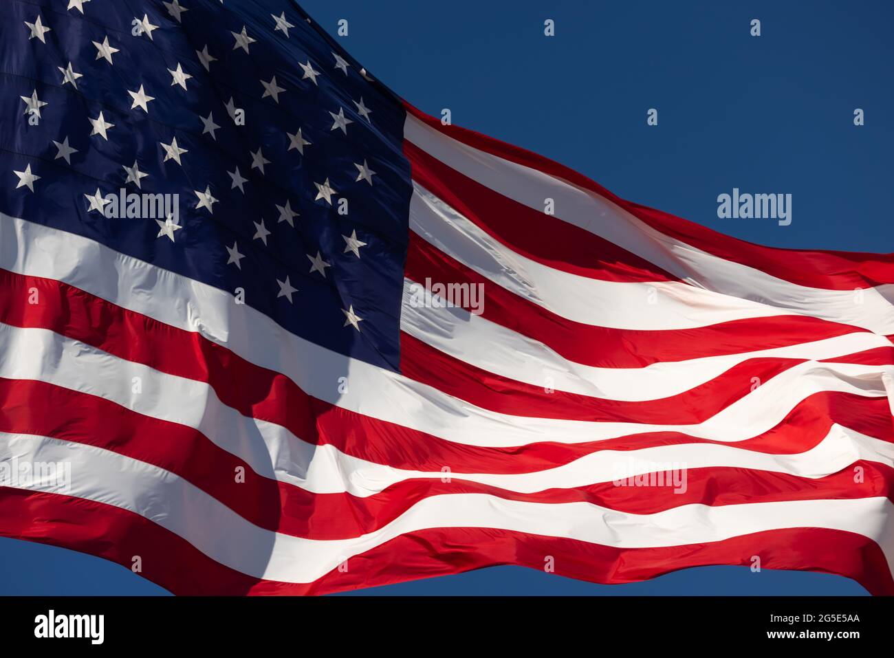 American Flag Waving In Wind Against a Deep Blue Sky Stock Photo - Alamy