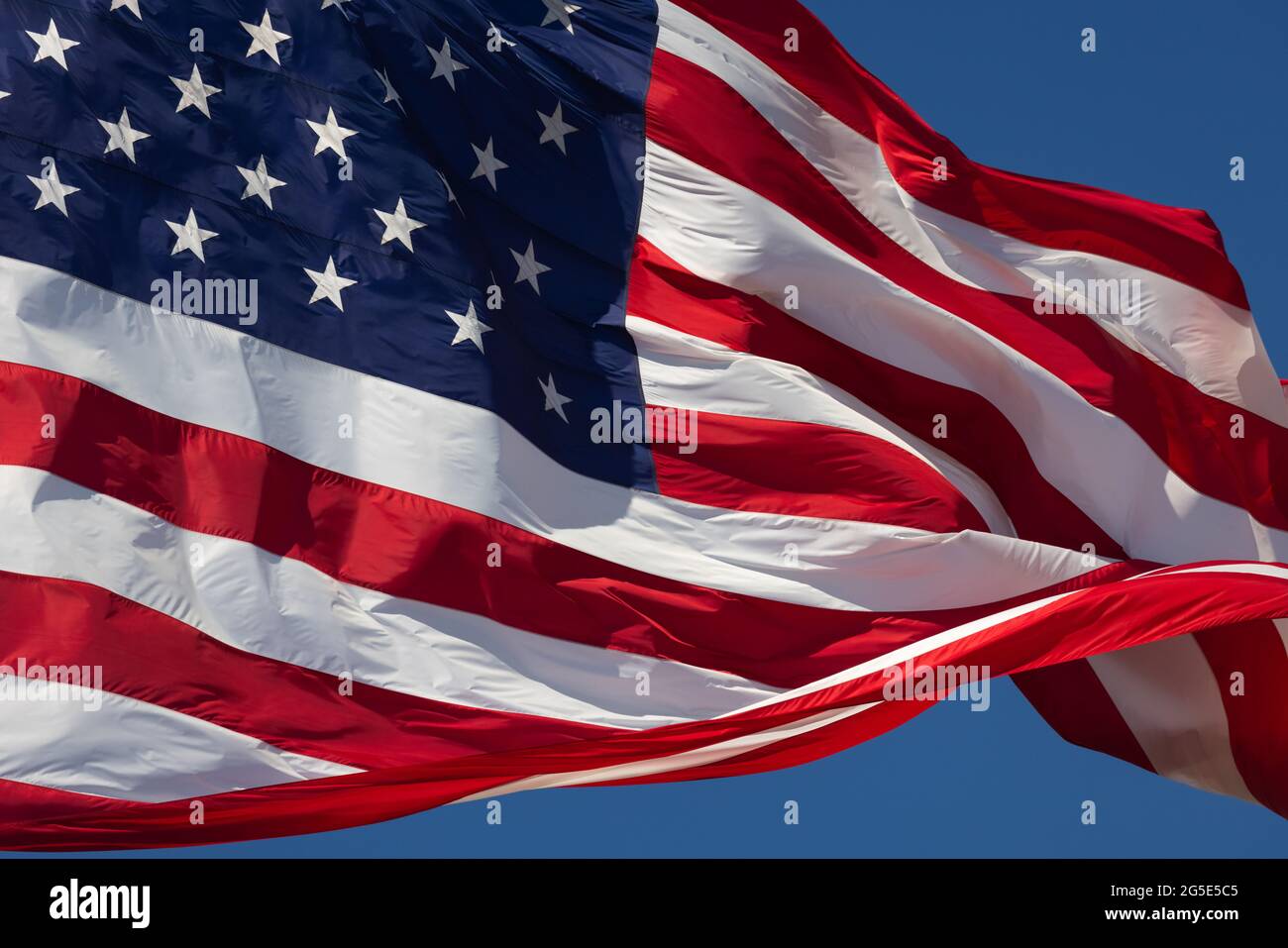 American Flag Waving In Wind Against a Deep Blue Sky Stock Photo - Alamy
