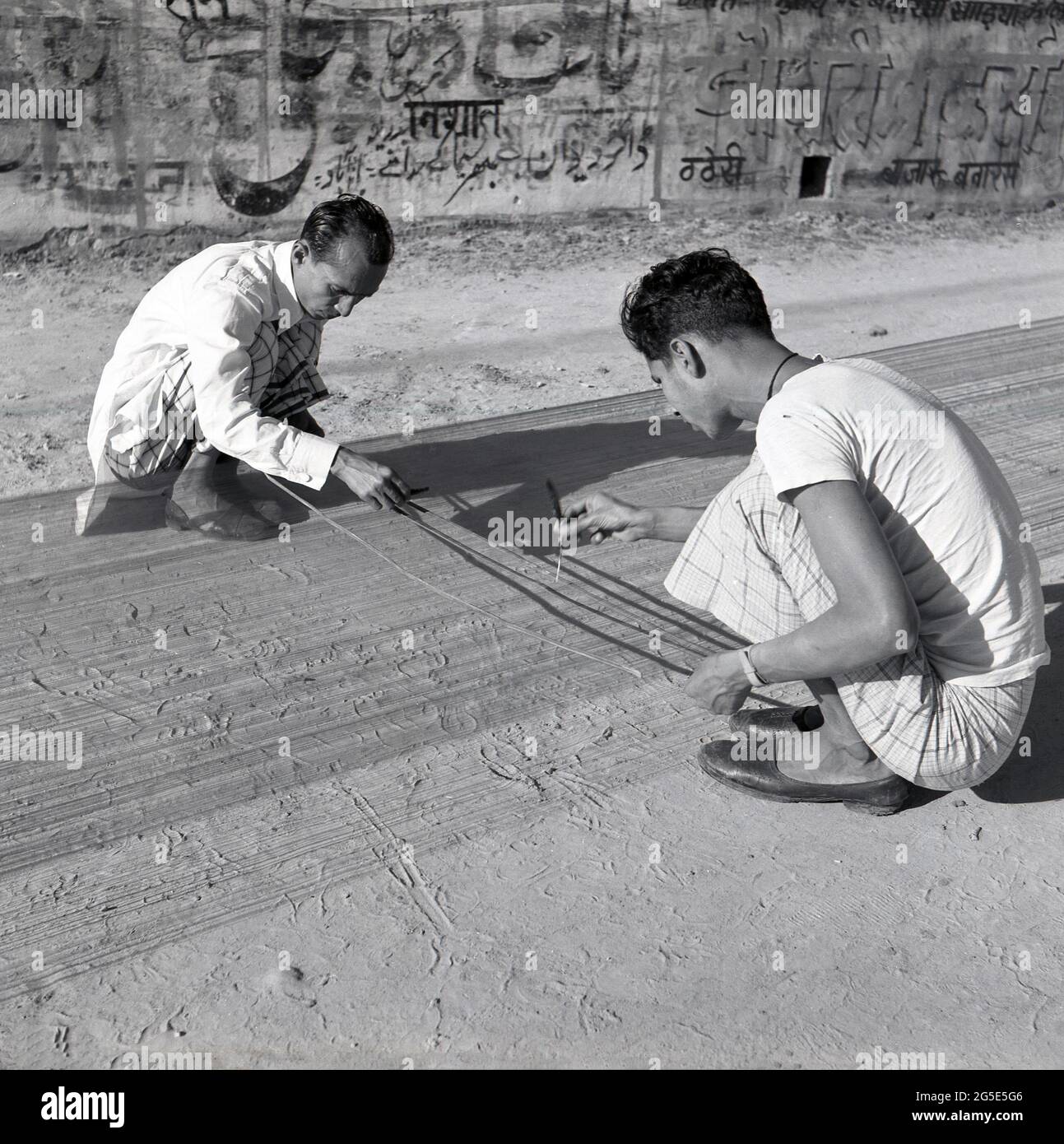 1950s, historical, outside in the street, two men stting on the dusty ground weaving, Benares, India. Stock Photo