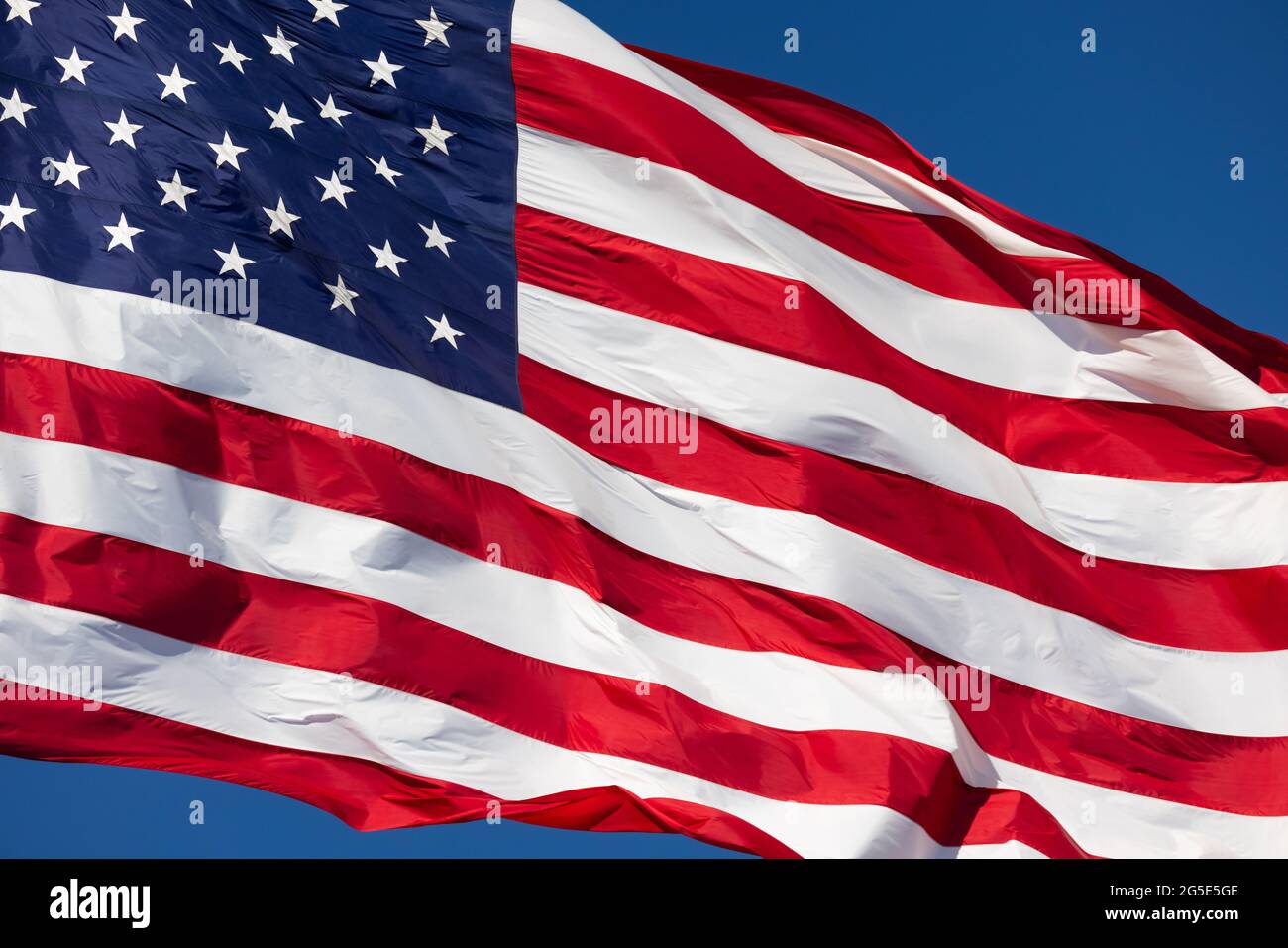 American Flag Waving In Wind Against a Deep Blue Sky Stock Photo - Alamy