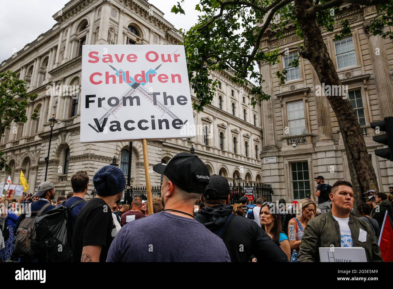 London, UK on June 26, 2021: Protesters holding placards demonstrate in front of Downing Street during Anti-Lockdown demonstration Unite for Freedom. People protesting against the lockdowns came together to raise their concerns regarding government vaccination legislations and freedom to travel and socialize. Stock Photo