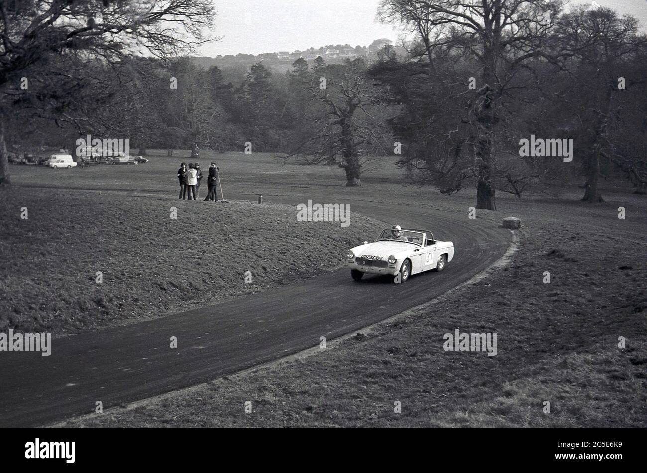 1960s, historical, open top MG Midget motor car going around a bend on a countryside rmotor racing circuit, England, UK. Note the solidarity straw bale on the corner. The small two-seater MG Midget sports car was made by MG from 1961 to 1979, orginally based on the Austin-Healey Sprite. Stock Photo