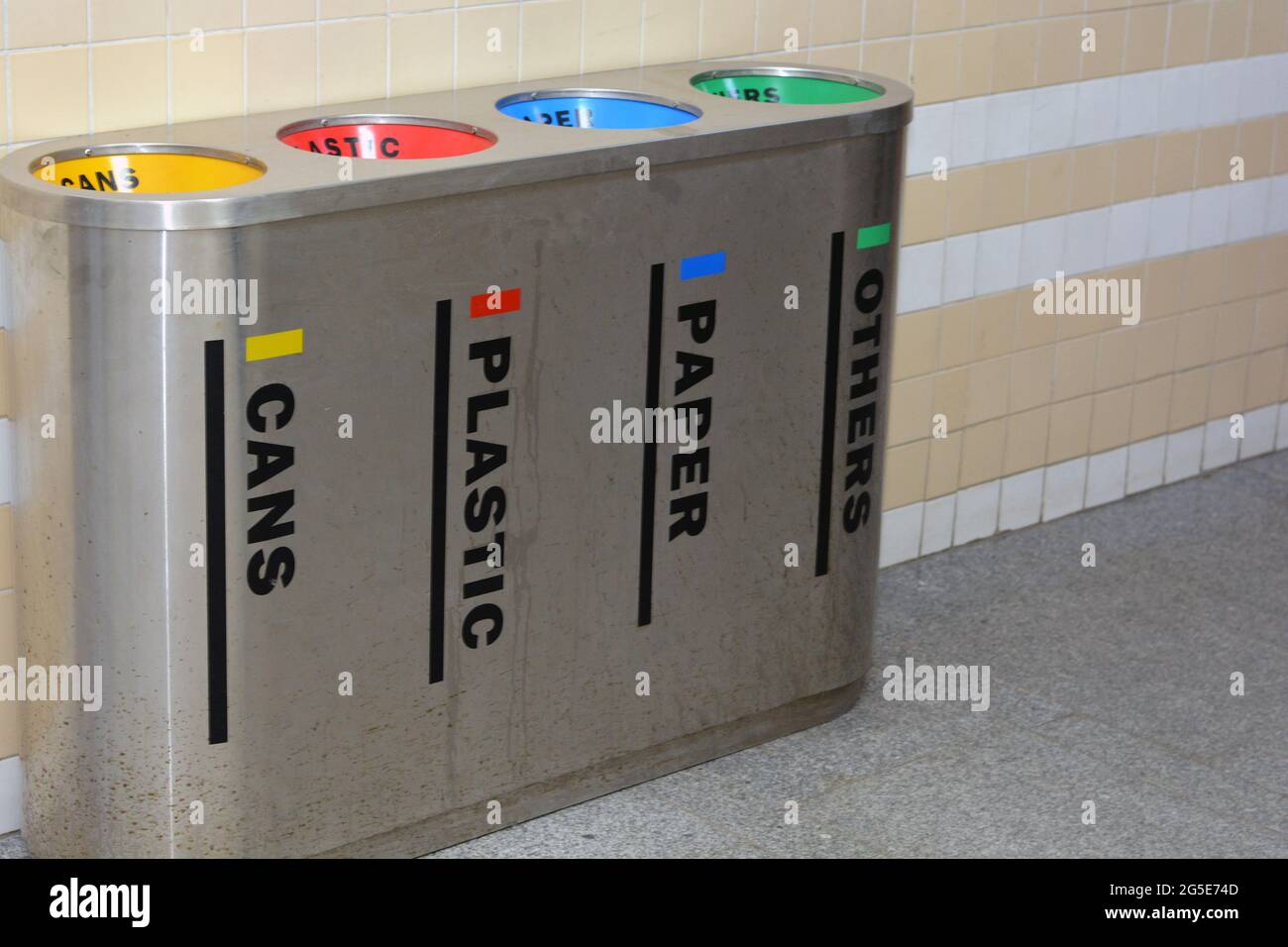 A metal trash bin for different garbage with an inscription in English