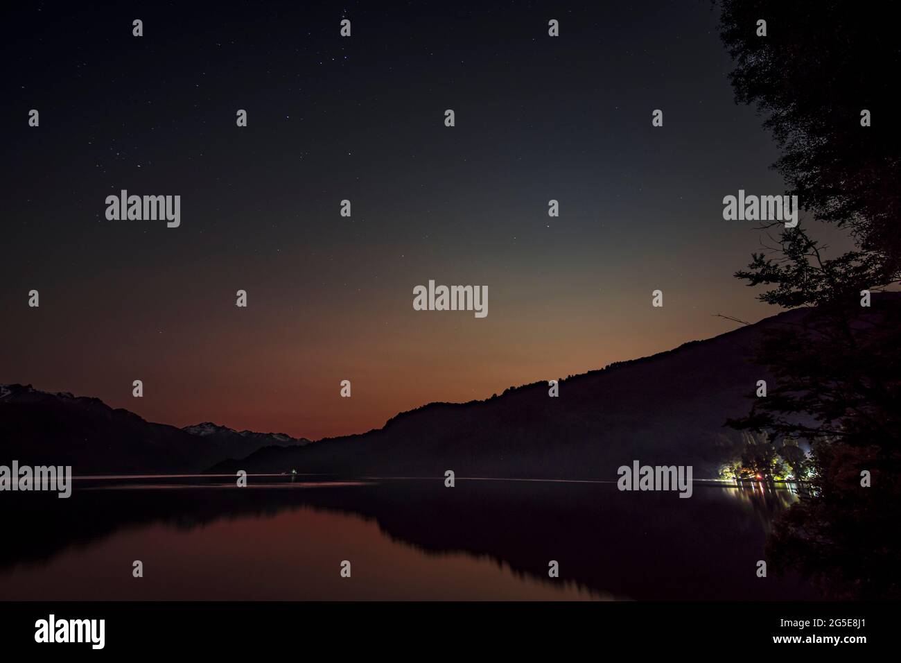 Quiet lake at late night in Los Alerces National Park. Lights can be seen from a base camp. Stock Photo