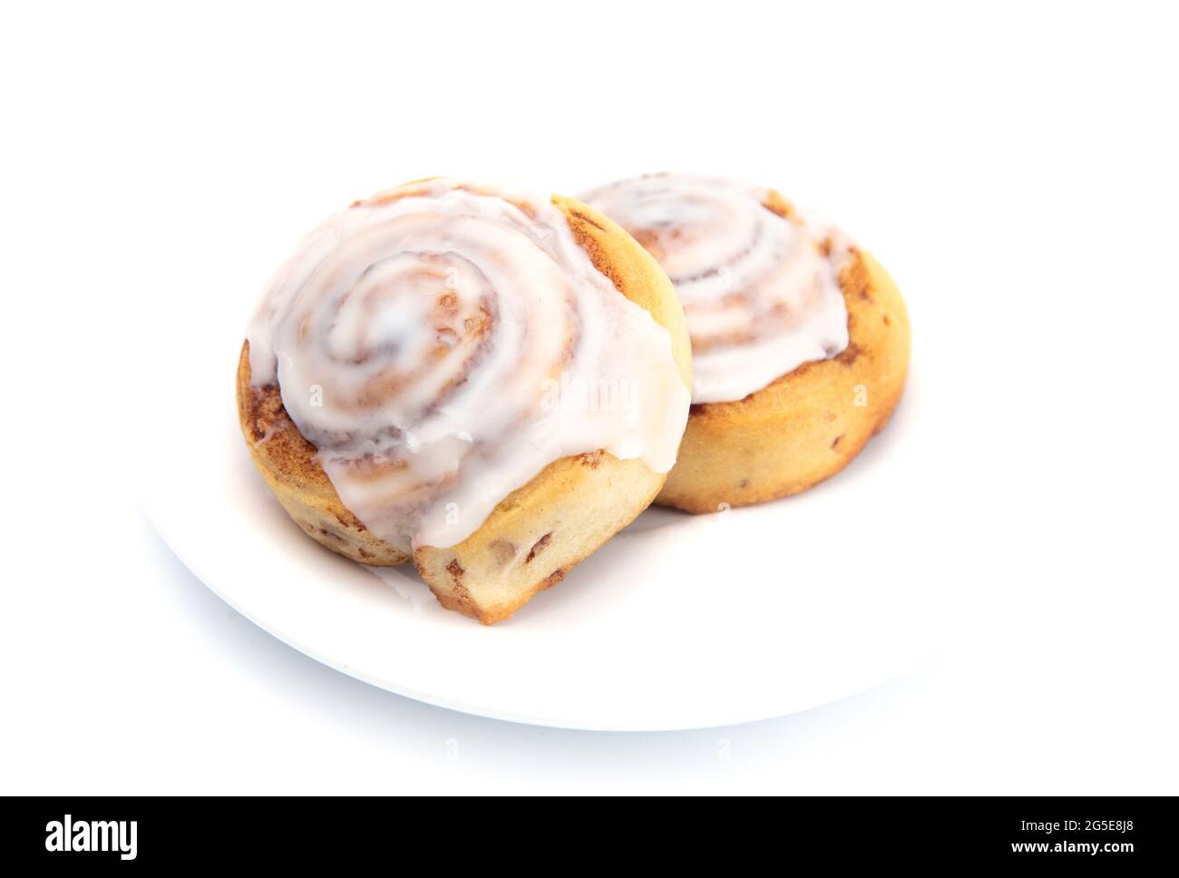 Two Frosted Cinnamon Rolls on a White Plate Stock Photo