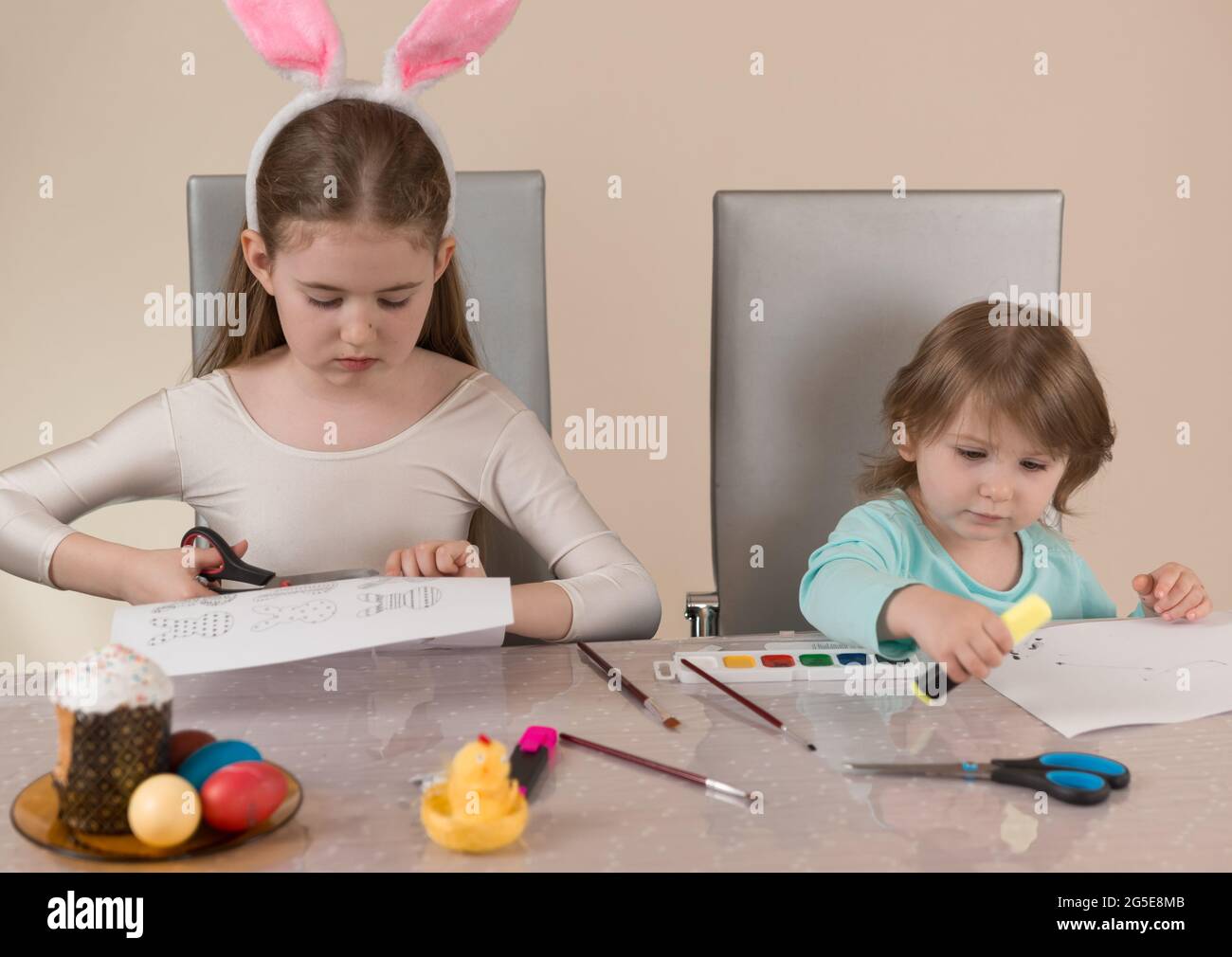 Two sisters at the table draw with paints and cut out paper crafts for ...