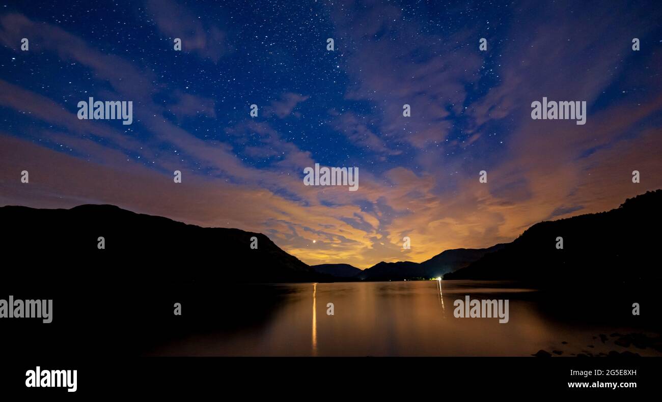 A view of a cloudy night sky over Ullswater with Mars shinning through the clouds Stock Photo