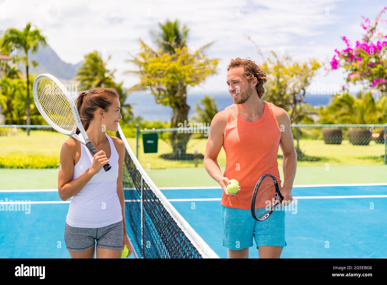 Tennis players friends having fun laughing playing on outdoor court. Couple or mixed double tennis partners outside in summer. Happy young people Stock Photo