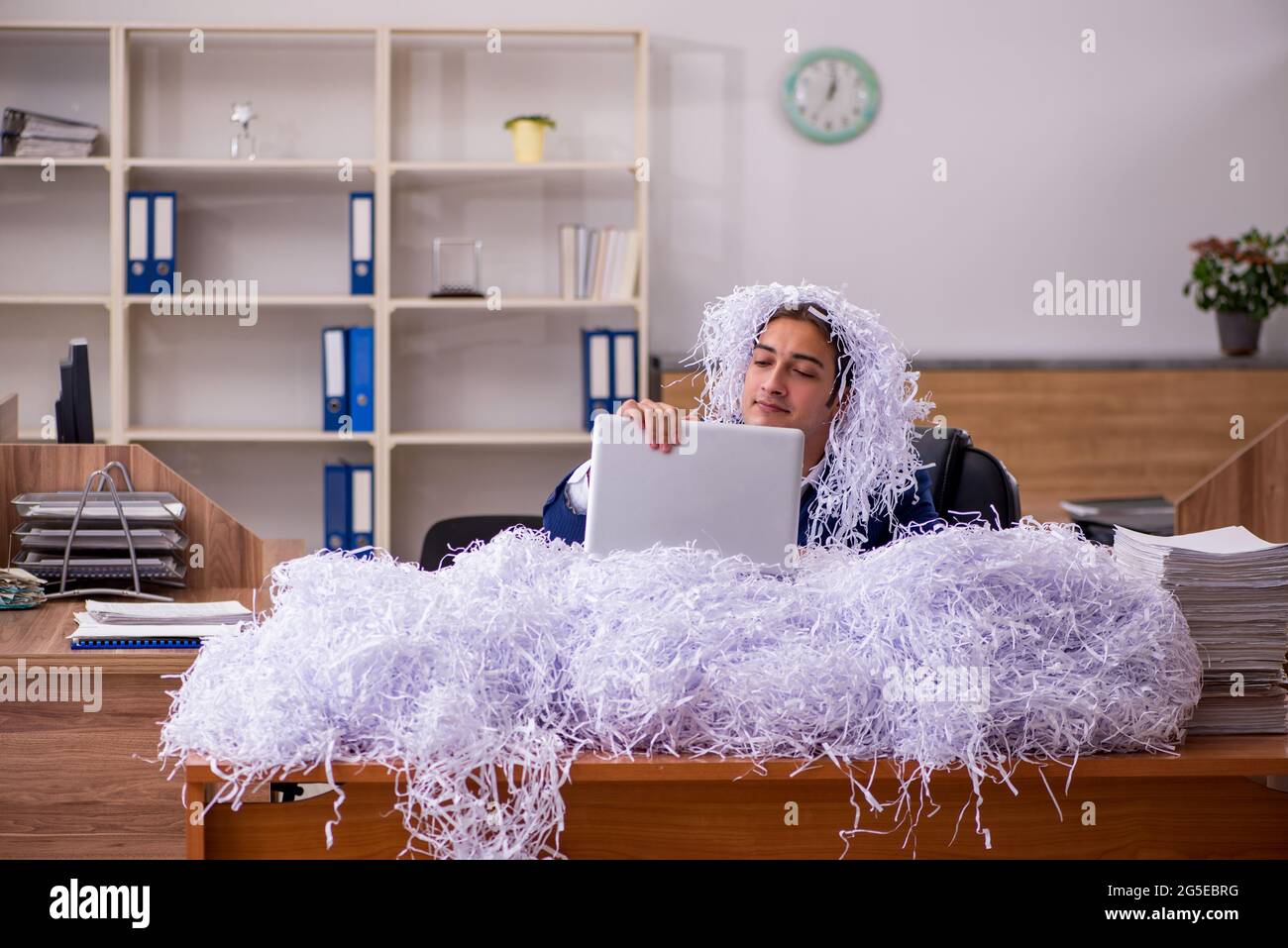 Young male employee cutting papers in the office Stock Photo - Alamy