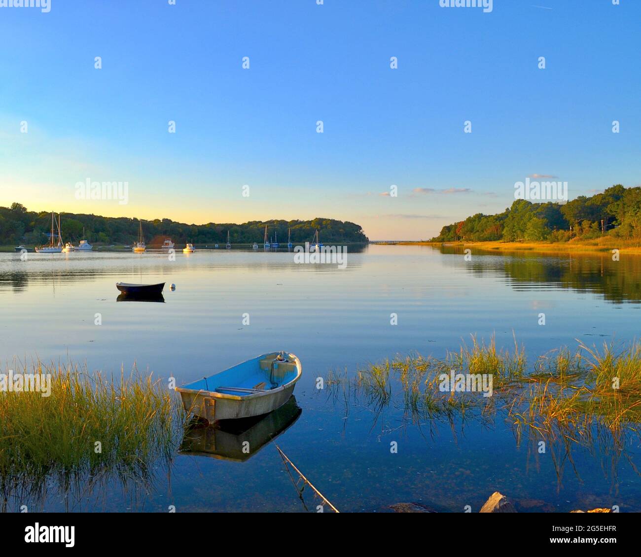 Two rowboats float motionless on a calm harbor in late afternoon autumn light.  Copy space. Stock Photo