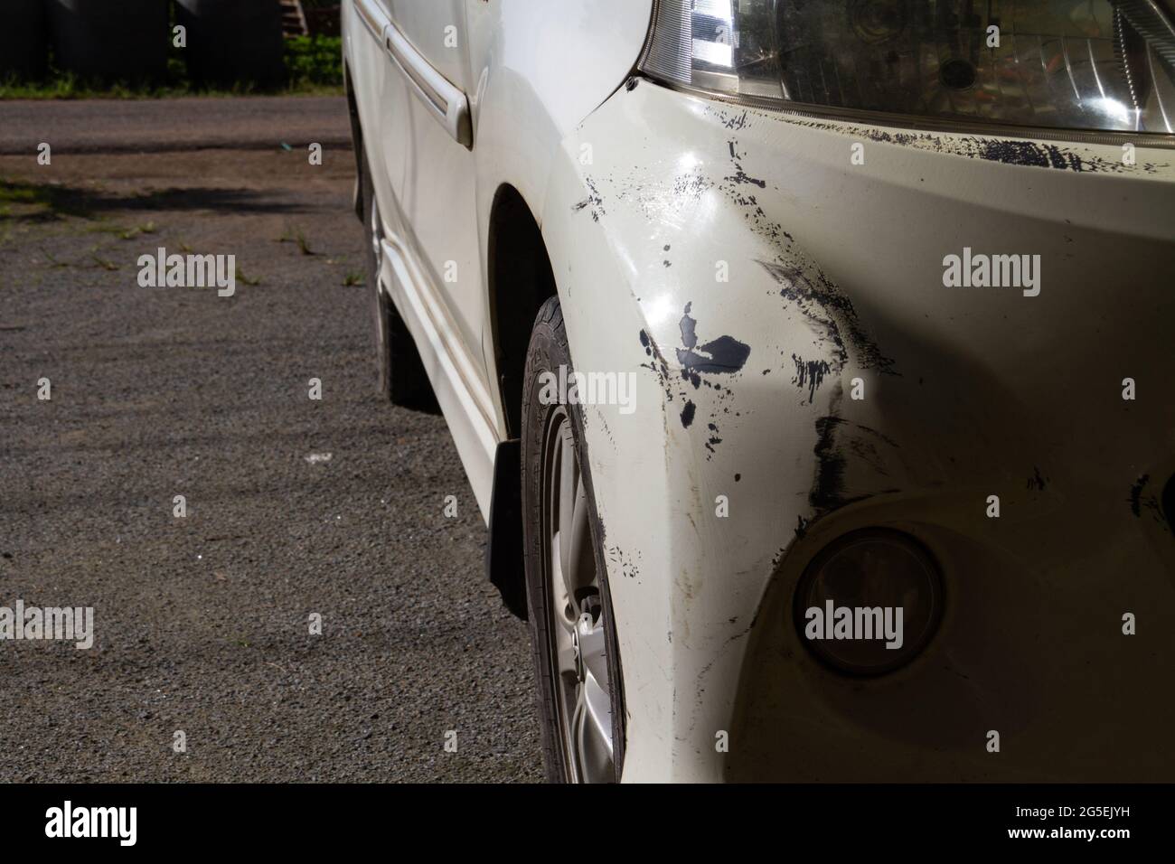 Damaged on front bumper. Scratches on white car after accident. In the