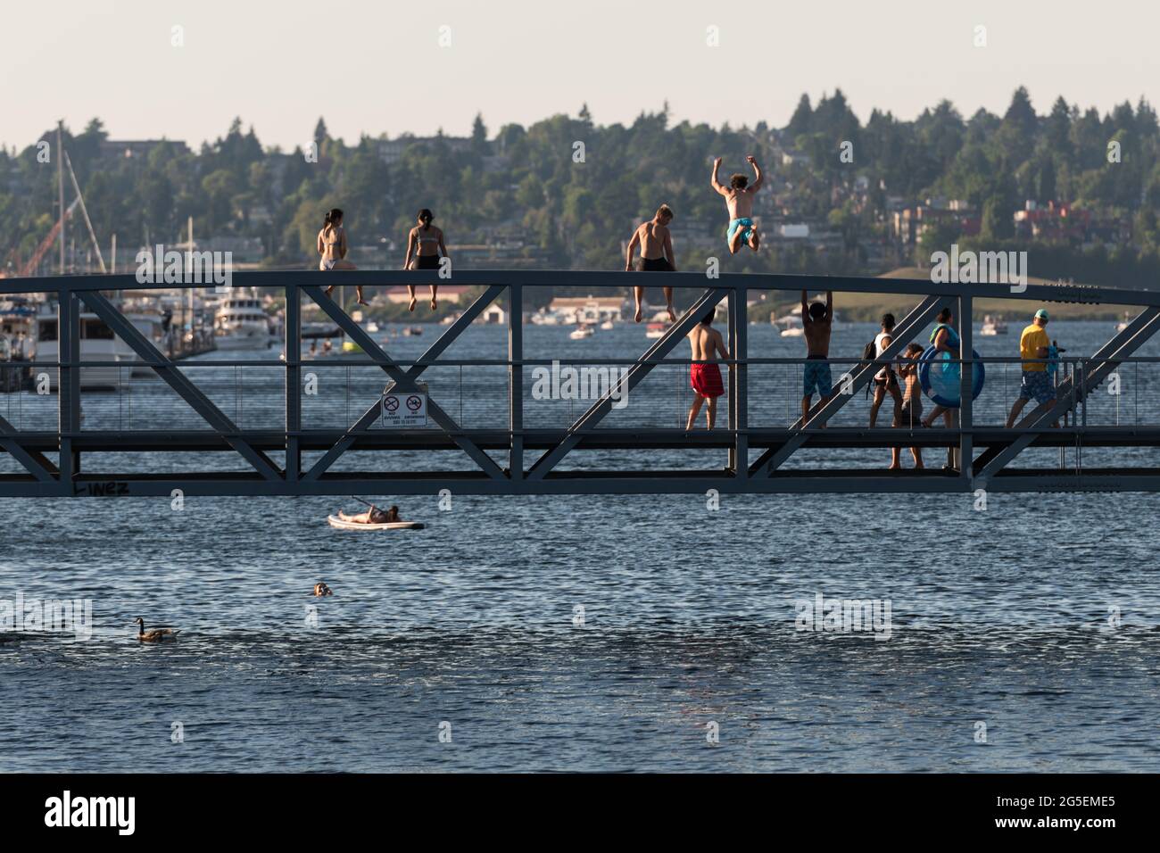 Seattle, USA. 26th Jun, 2021. As sweltering heat envelops Seattle, a man jumps from the South Lake Union Park Bridge to the icy water below. The PNW is in the midst of a heat wave that has pushed the Puget sound to historic record three-digit temperatures for the next three days. Credit: James Anderson/Alamy Live News Stock Photo