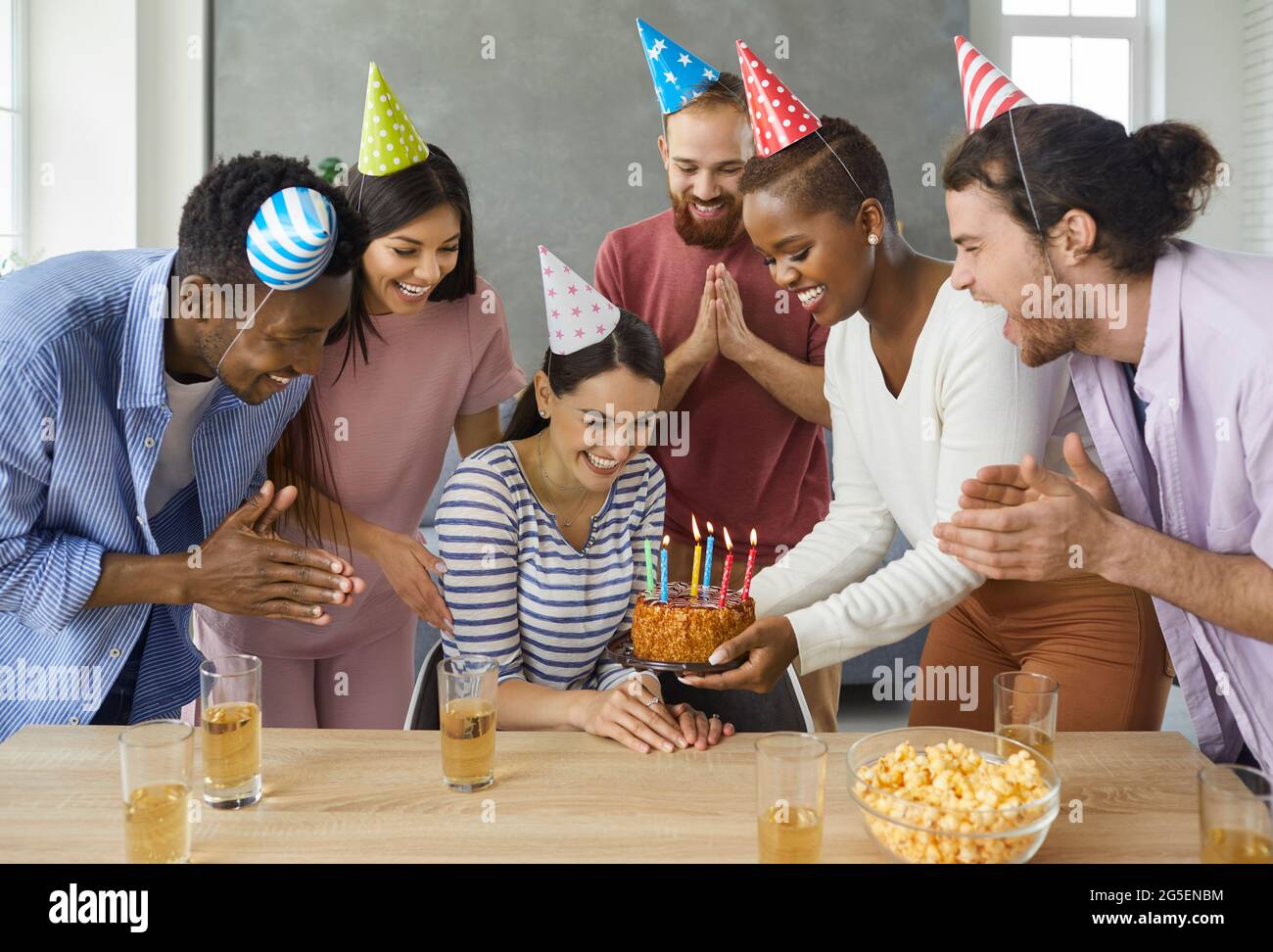 Woman receives birthday greetings and a delicious cake with burning candles given to her by friends. Stock Photo
