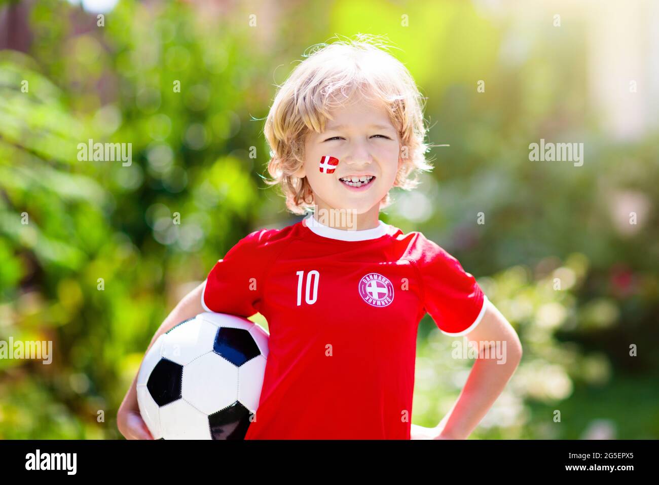 Denmark football fan cheering. Danish kids play soccer and celebrate victory on outdoor field. Danmark team supporter. Little boy in Dansk flag jersey Stock Photo