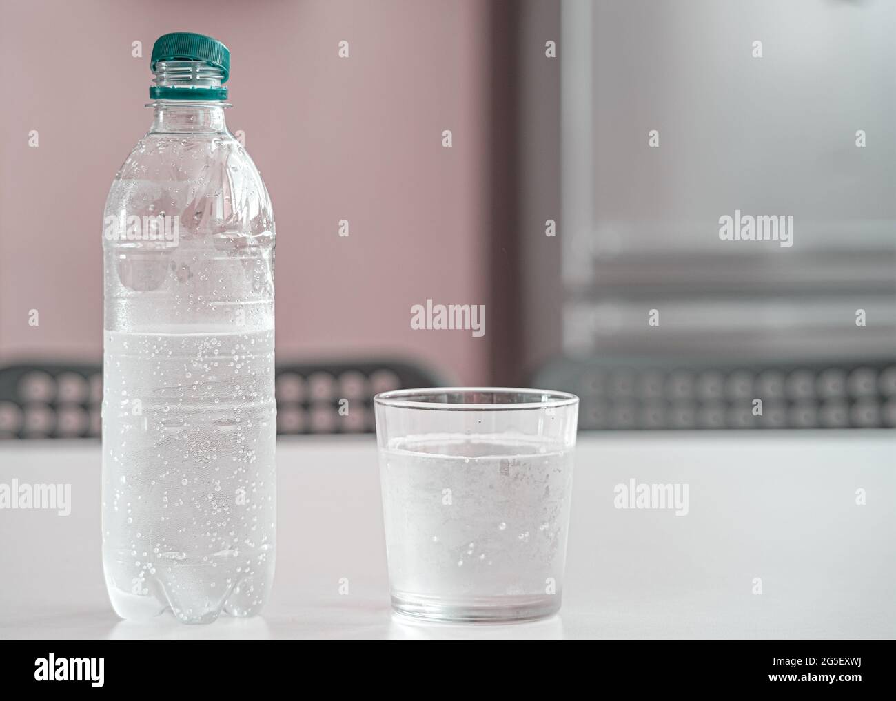 bottle of fresh water backlighting on background with water droplets Stock Photo