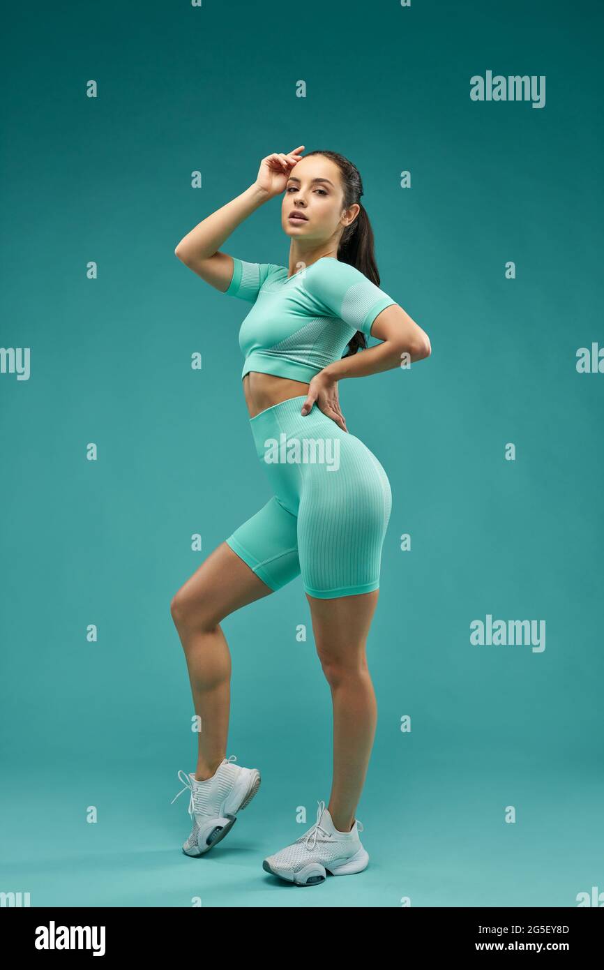Sporty young woman posing against green background Stock Photo