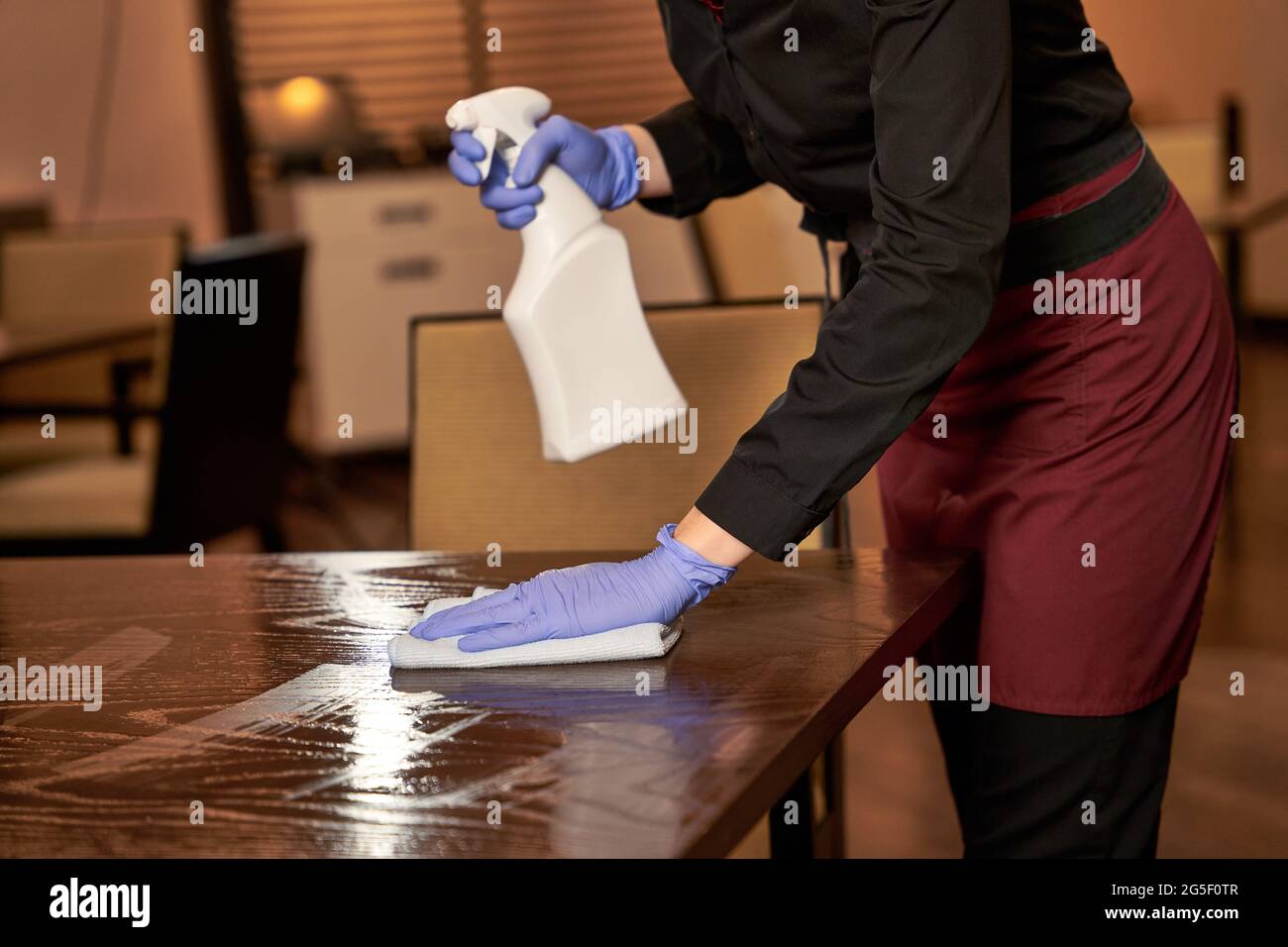 Restaurant worker washing a sprayed table with cloth Stock Photo