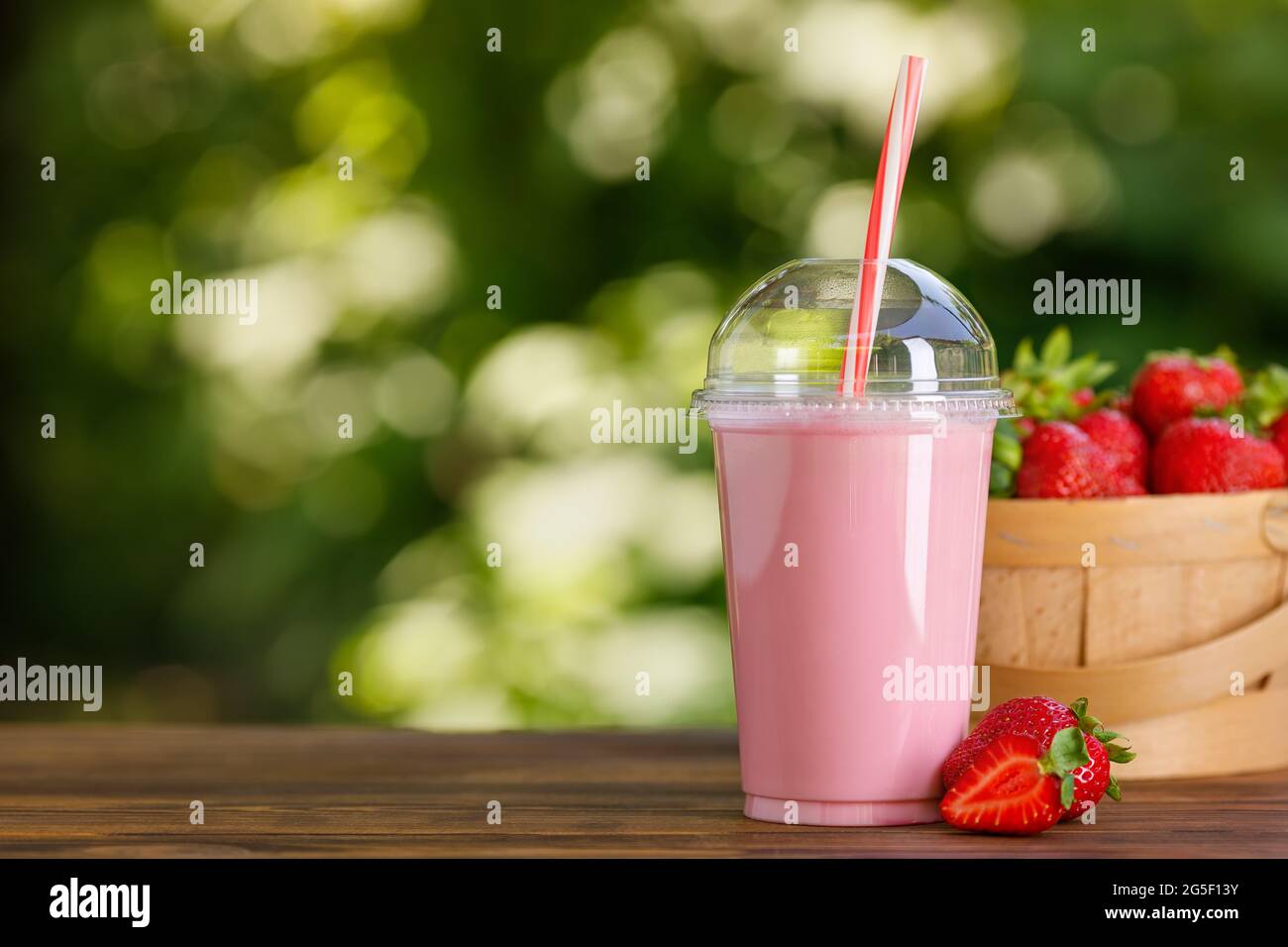 strawberry milkshake in disposable plastic glass on wooden table Stock Photo