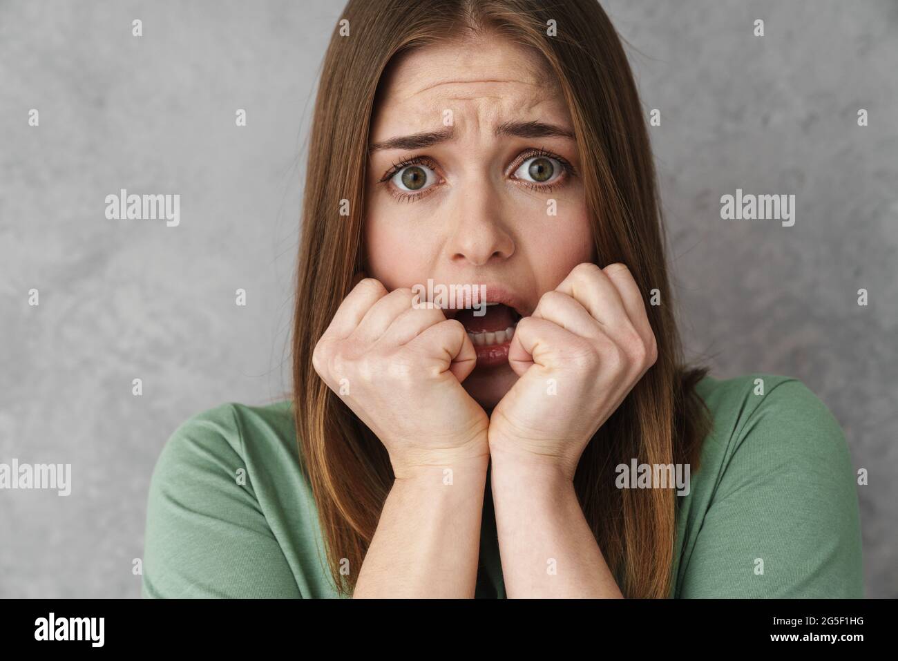 Close up of a scared shocked blonde young woman gesturing over gray