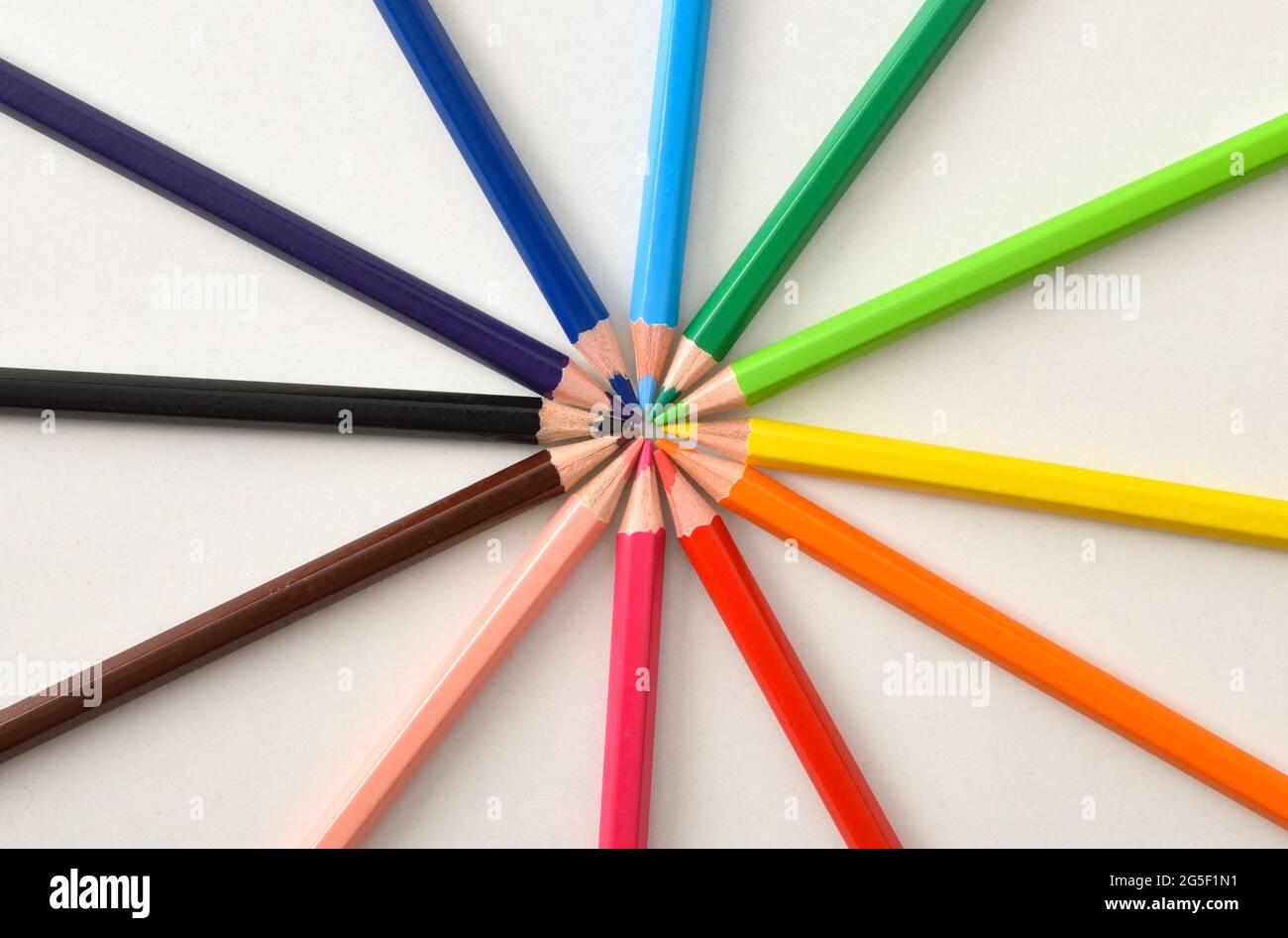 Background detail with color pencils placed on circle on white table. Top view Stock Photo